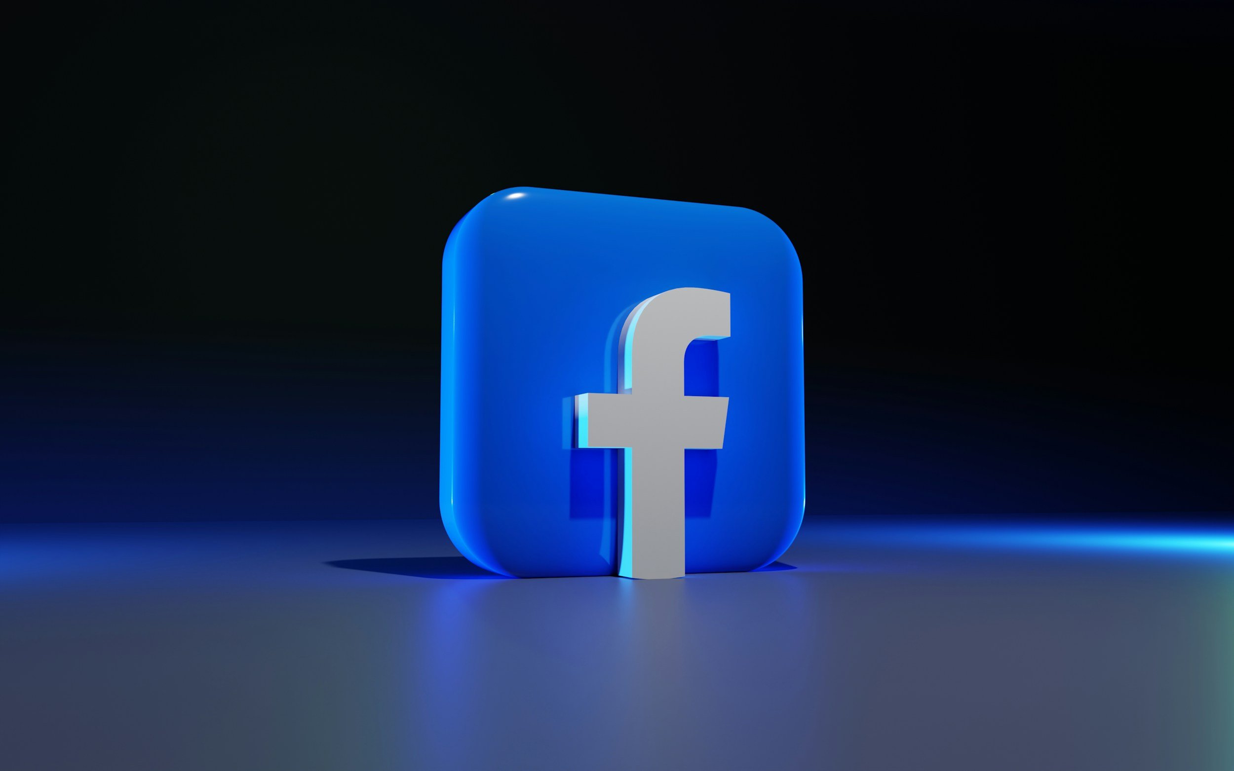 A 3D digital rendering of the Facebook logo, featuring a blue square with rounded edges and a white lowercase 'f' in the center, set against a dark background with a subtle blue glow.