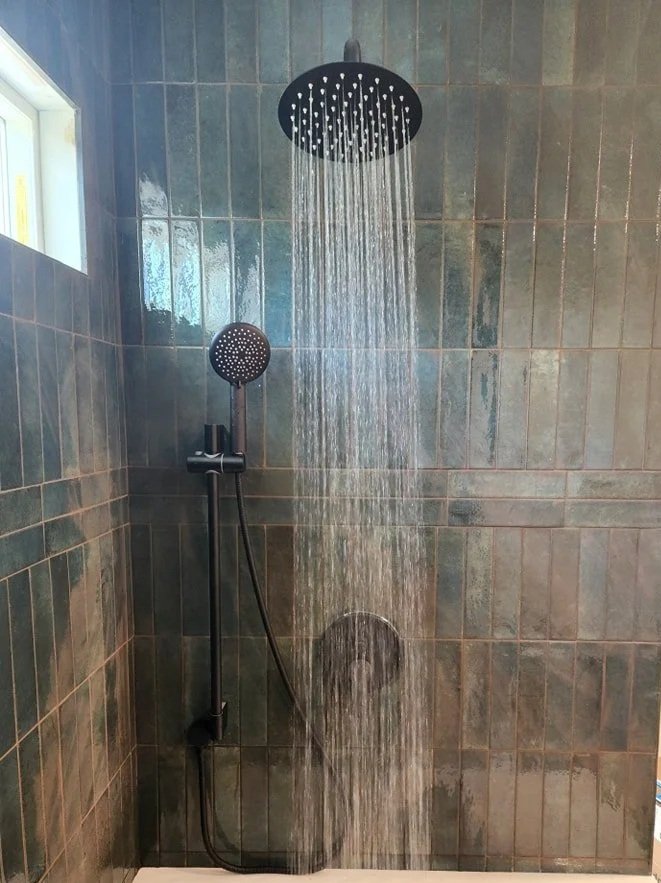 A shower with a rainfall showerhead and a handheld shower, both mounted on a tiled wall.