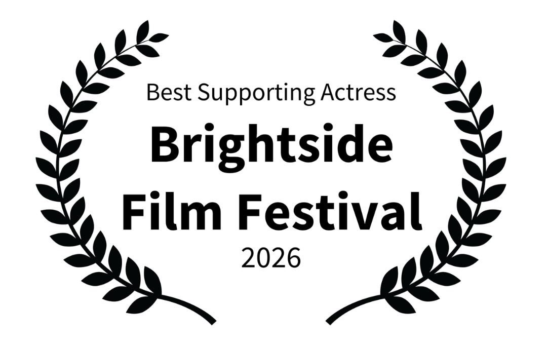 Famous actor on stage holding an award, with a black backdrop displaying text and laurel wreath design.