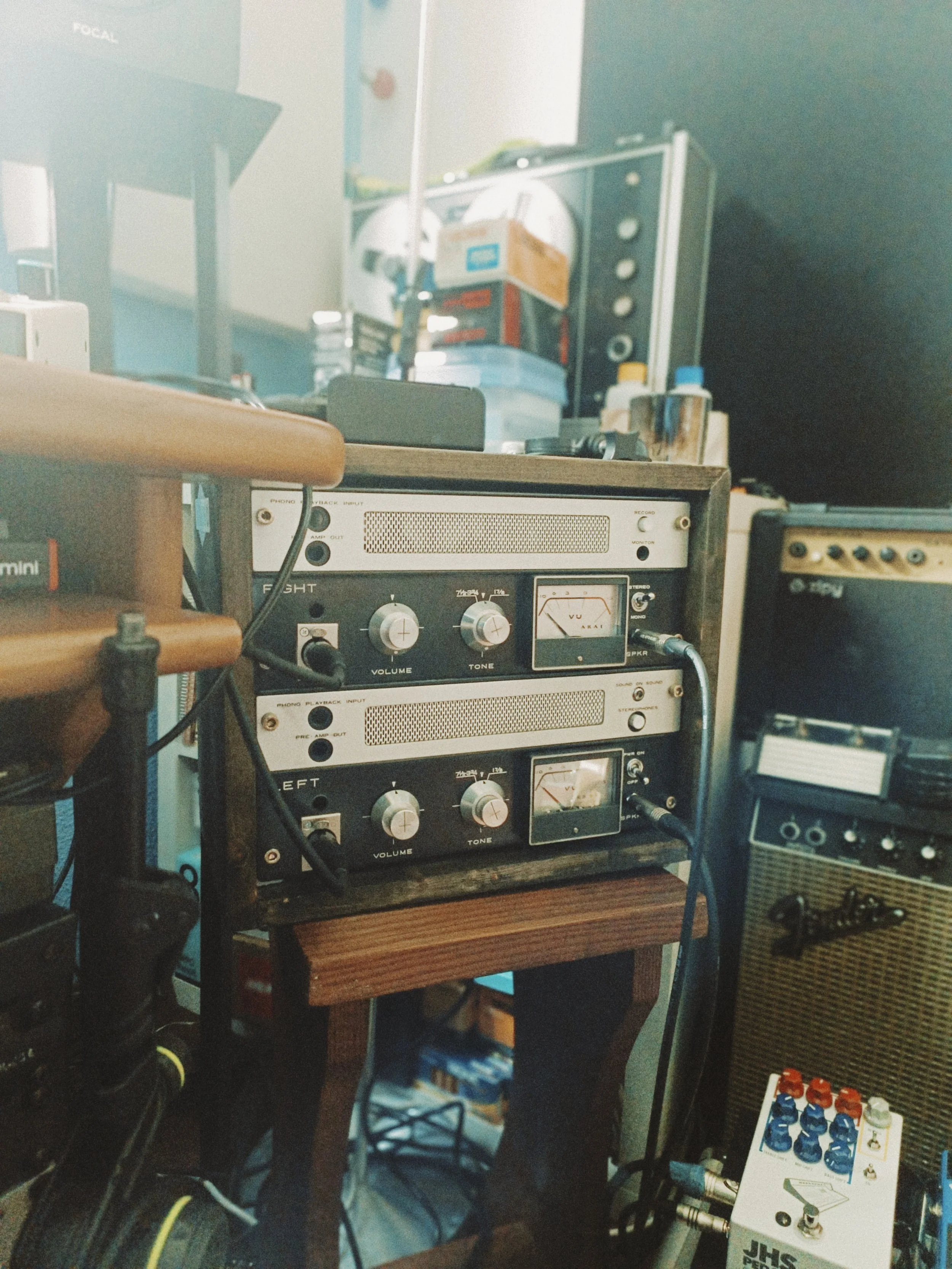 Recording studio equipment including audio interfaces, speakers, and audio gear on a wooden table.