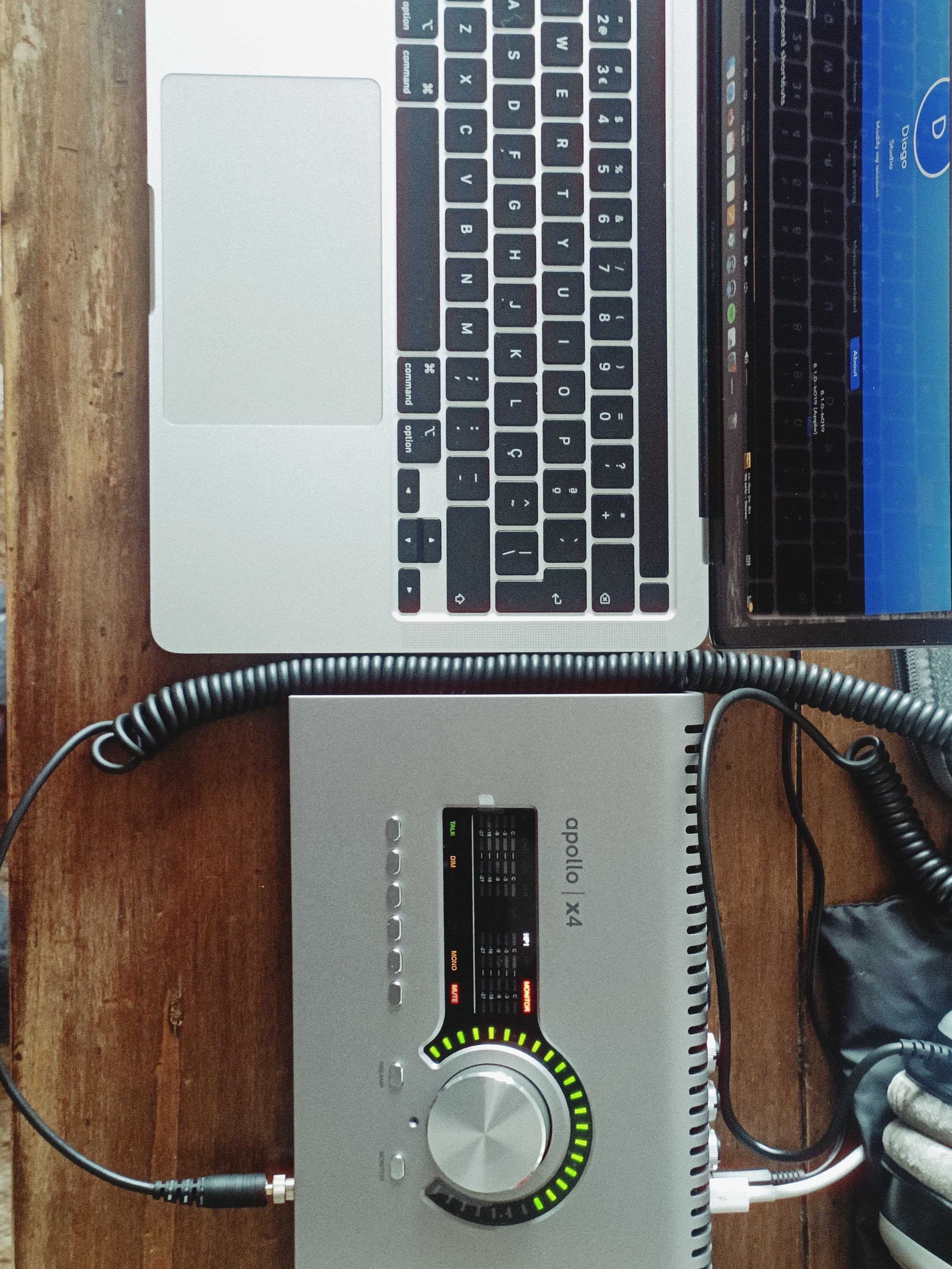 A desktop photo showing a laptop keyboard, a DJ mixer with colorful LED lights, and a vintage telephone cord on a wooden surface.