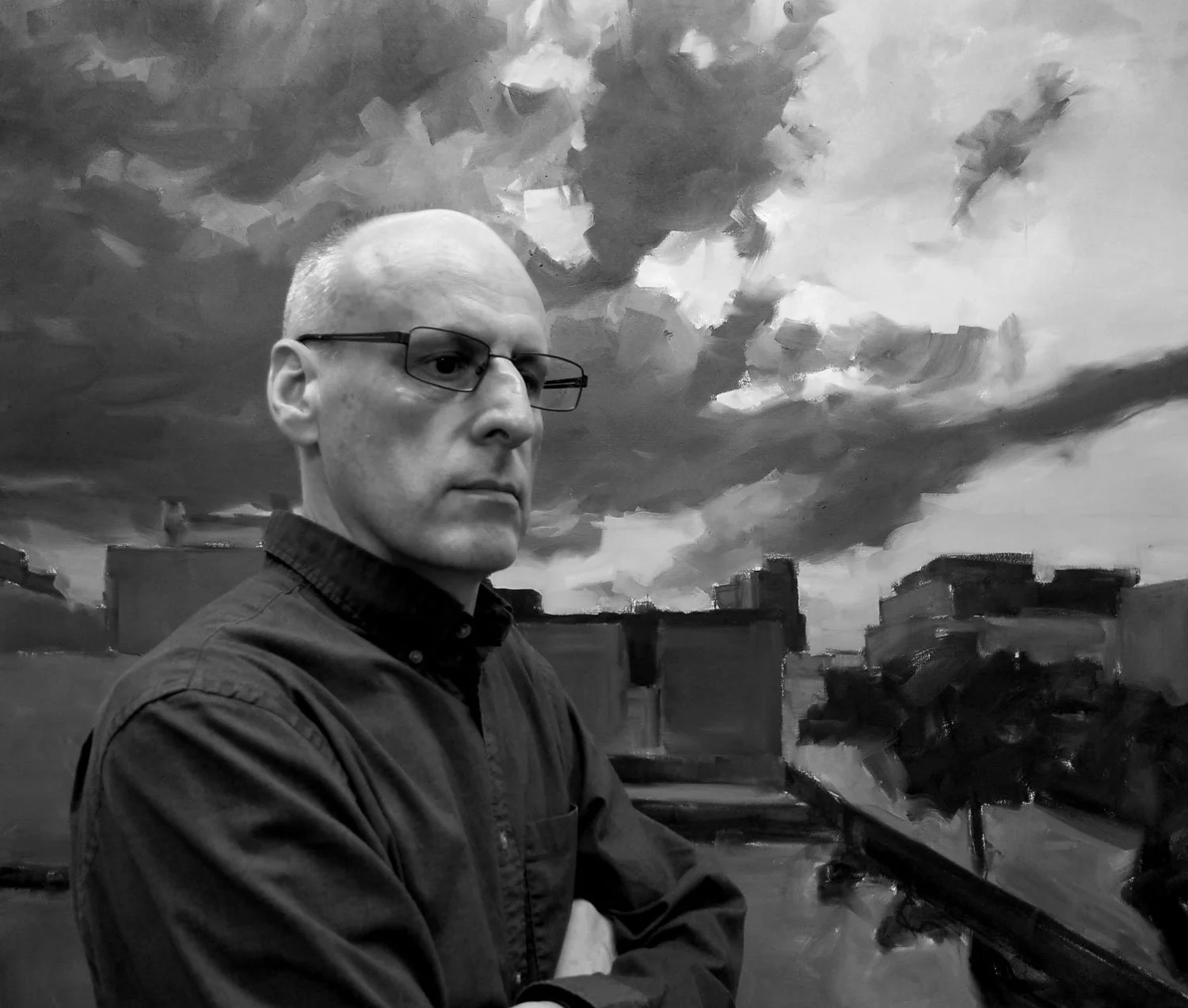A black-and-white portrait of a man with glasses, standing before a painted backdrop of a dramatic cloudy sky and industrial buildings.