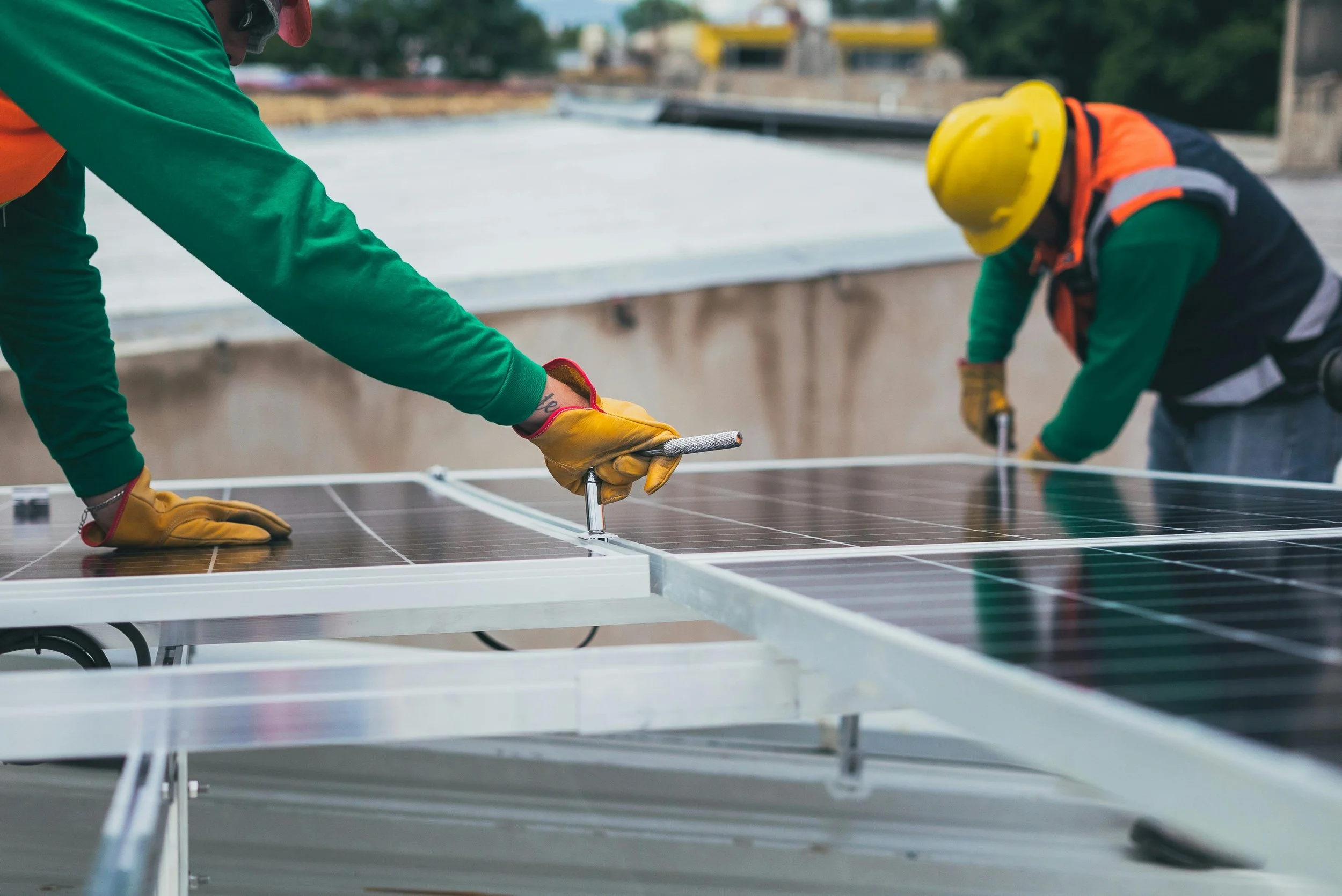 Workers installing solar panels on a metal frame outdoors.
