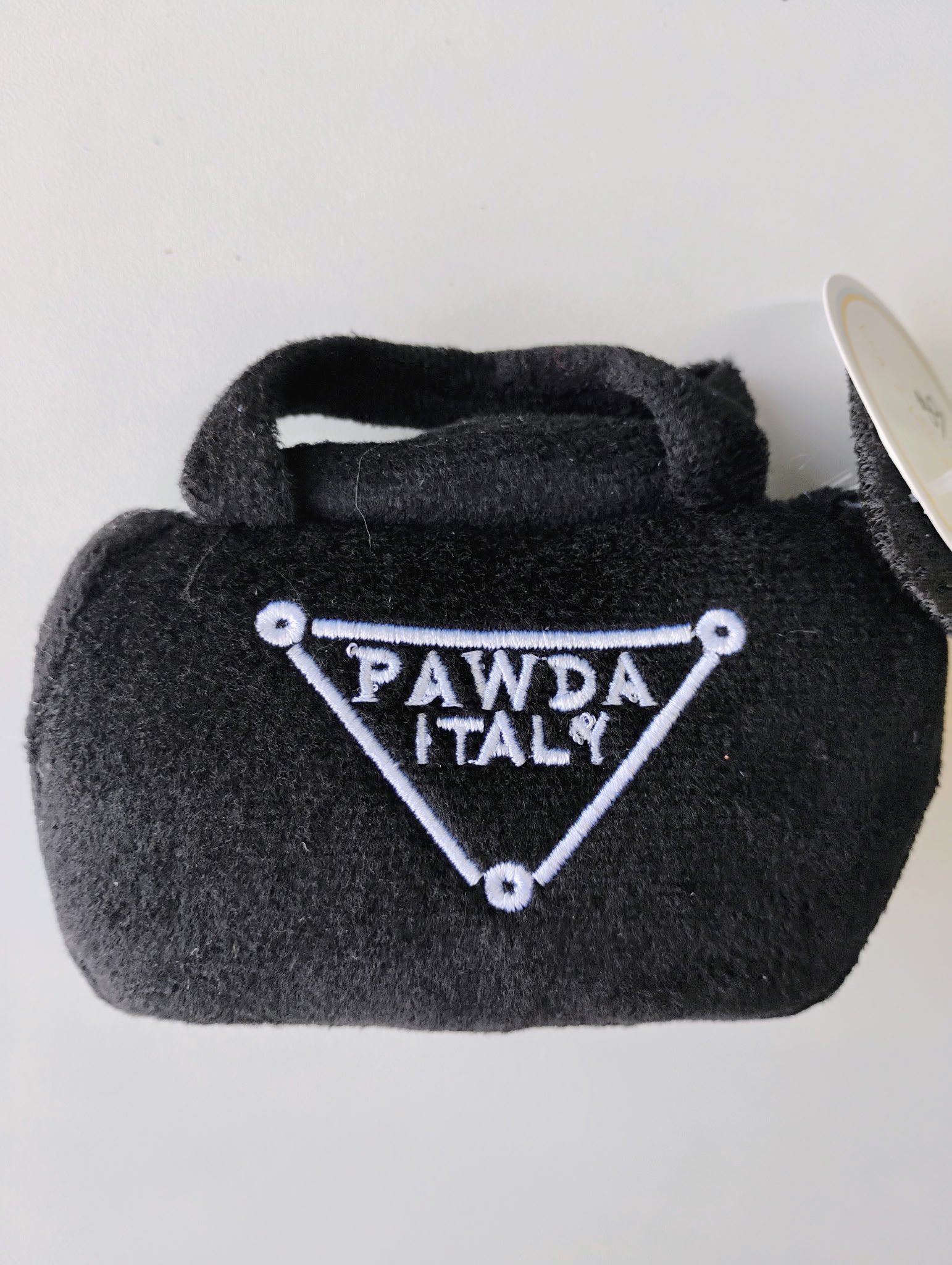 Black fuzzy craft pouch with white embroidered text 'Pawda Italy' and paw print design, placed on a white surface.