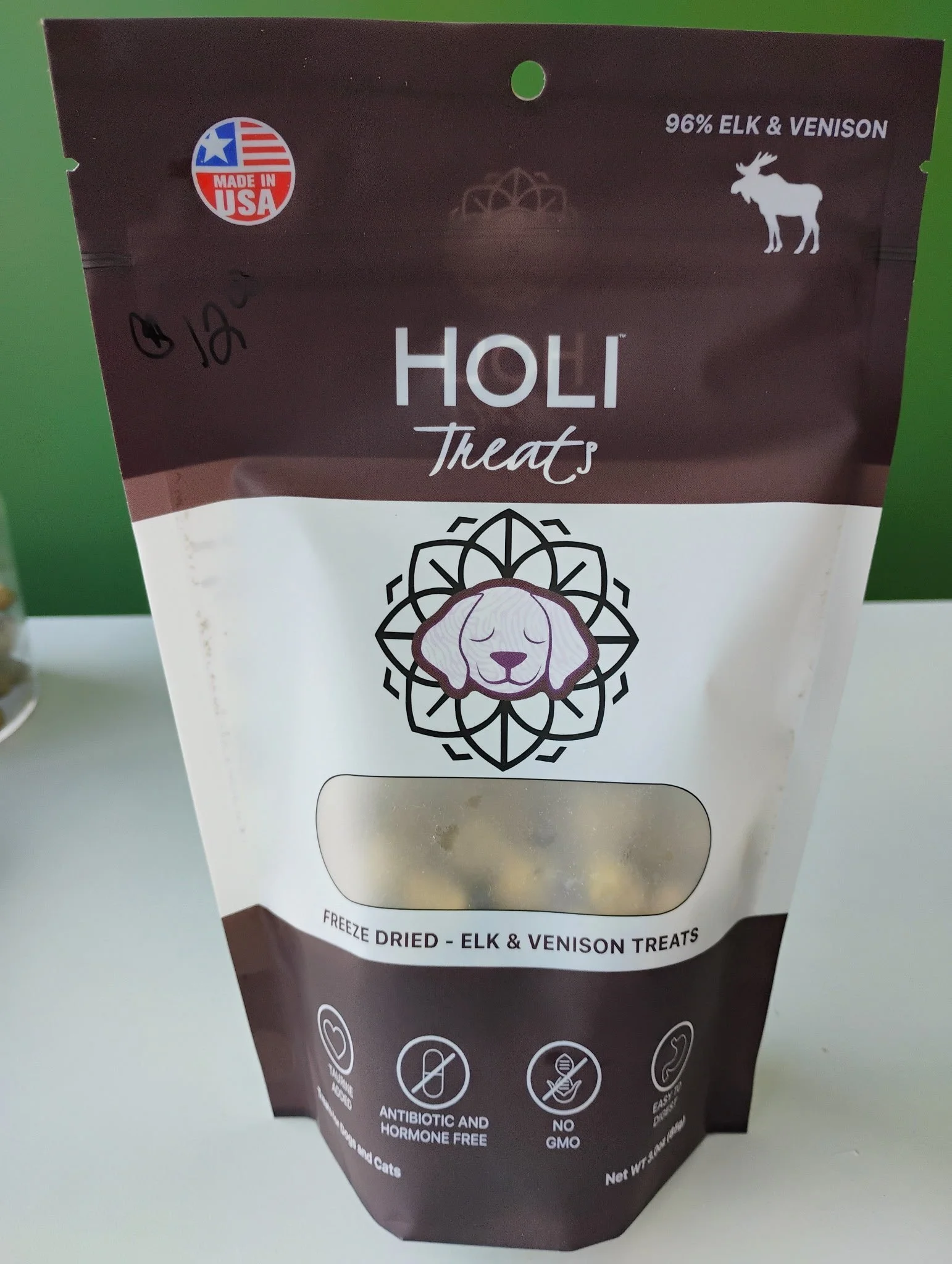 Package of Holi Treats freeze-dried elk and venison treats with a label indicating it is made in the USA, contains 96% elk and venison, and is antibiotic, hormone free, GMO-free, and easy to digest.
