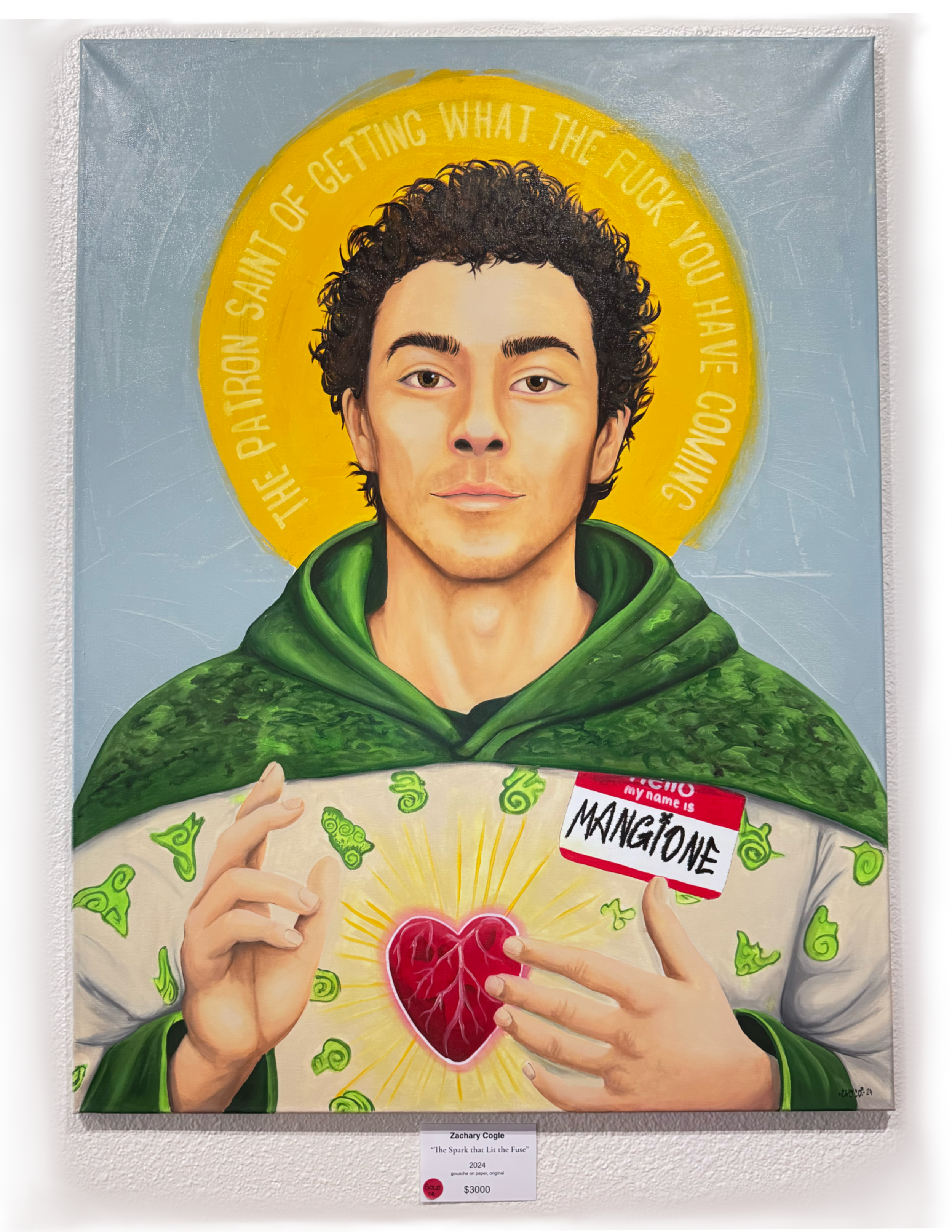 A colorful painting of a person with curly hair and light skin, holding a heart with an illustration of a brain inside. The person is wearing a green hoodie, and behind their head is a yellow halo with the text "The parasite of getting what the fuck you have - coming." They have a focused expression and are pointing at the heart, which displays a detailed brain illustration. The artist's name, title, year, and price are visible below the artwork.
