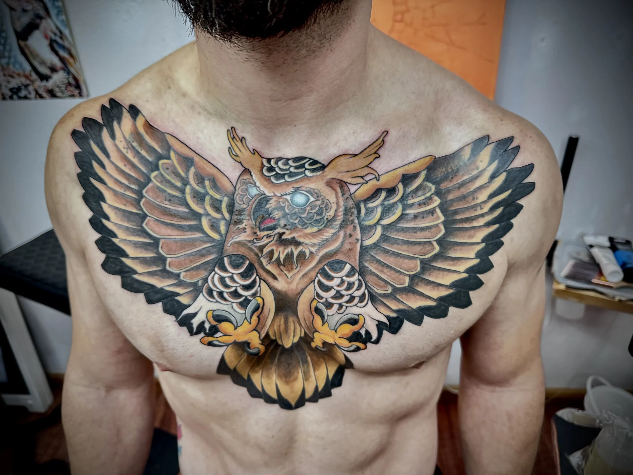 Colorful tattoo of an eagle with spread wings on a person's chest.