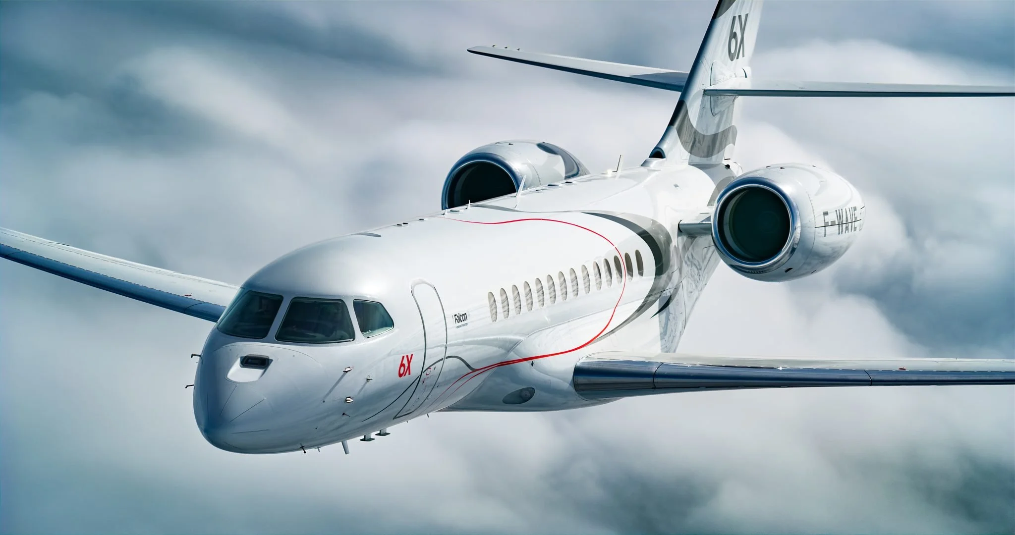 A white private jet flying in cloudy skies with sleek design and tinted cockpit windows.