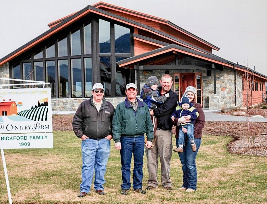 Family group standing in front of a modern farmhouse on a farm.