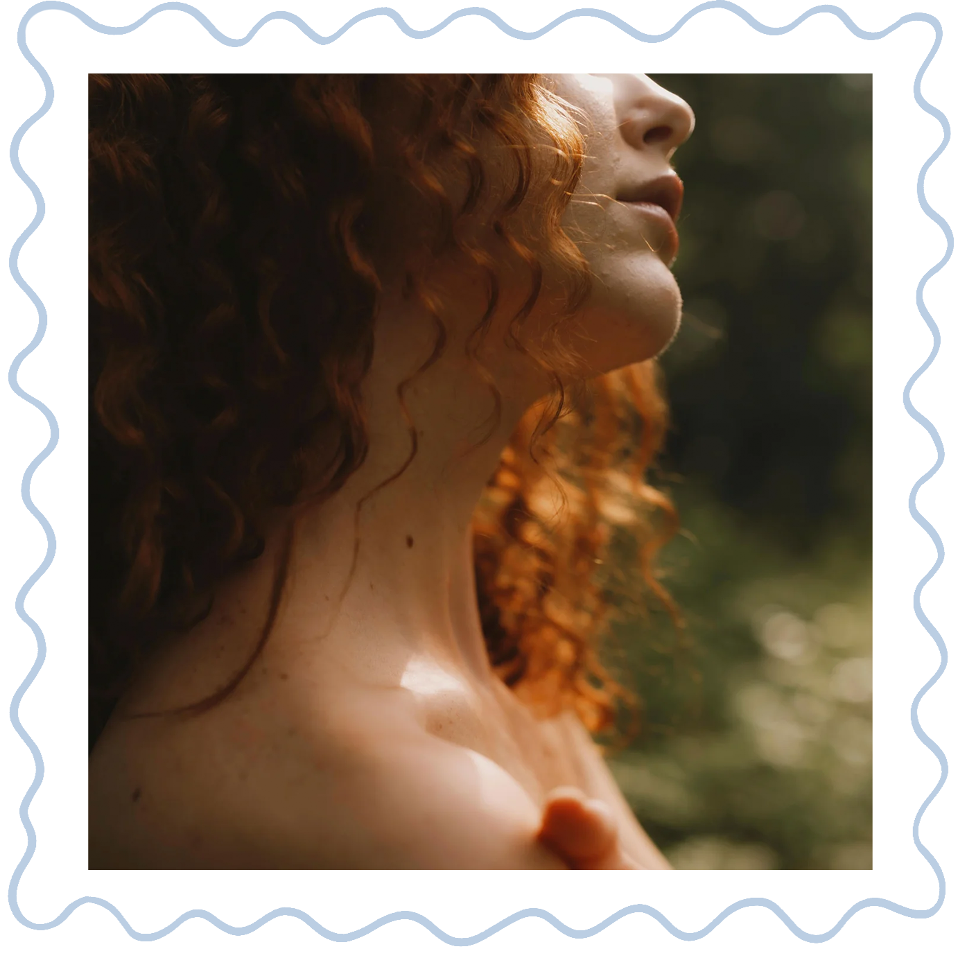 Close-up of a woman's face and shoulder with curly red hair, with sunlight highlighting her skin and hair outdoors.