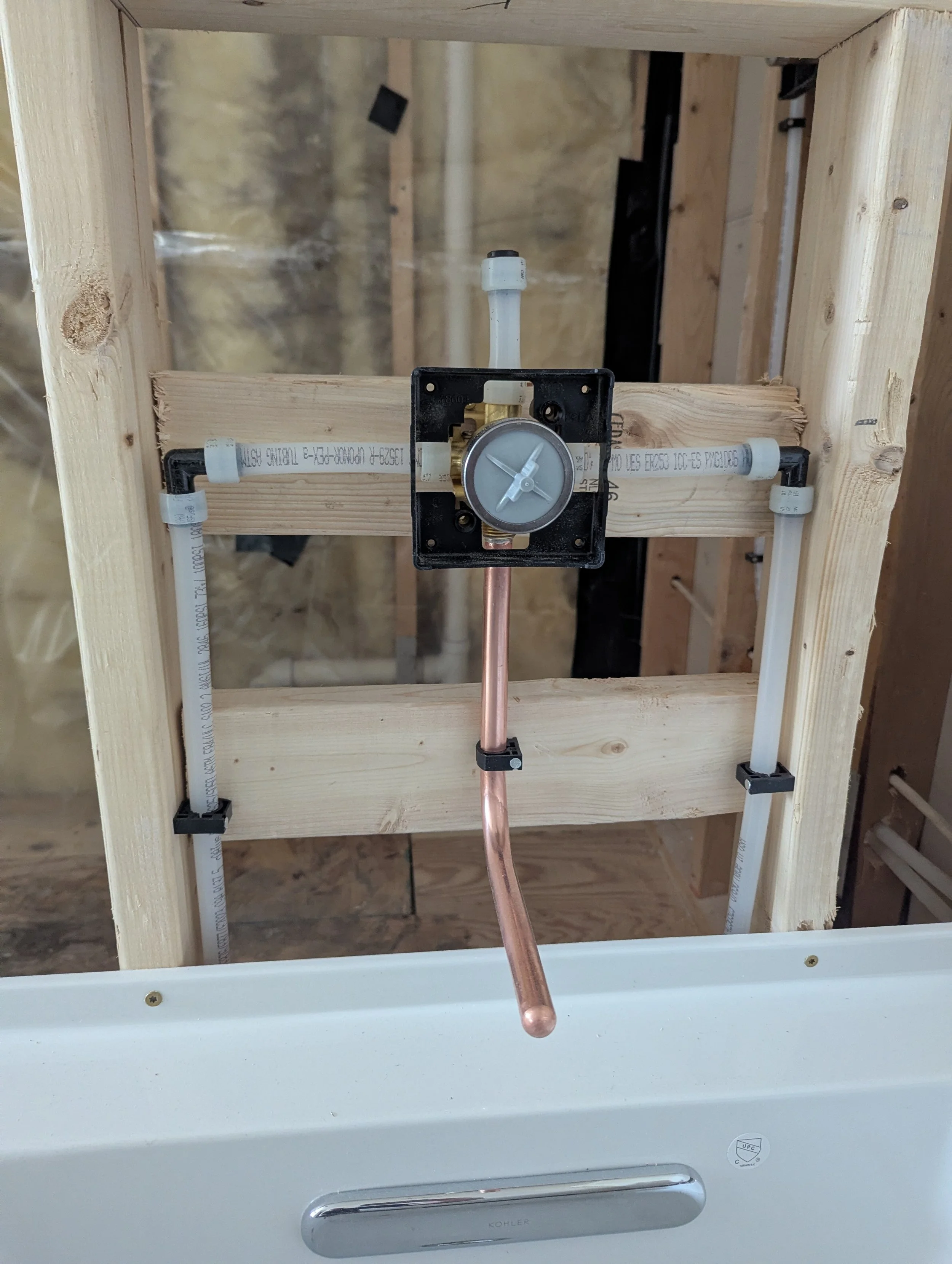 Installation of a new toilet tank flush valve, with plumbing parts and wooden framing visible.