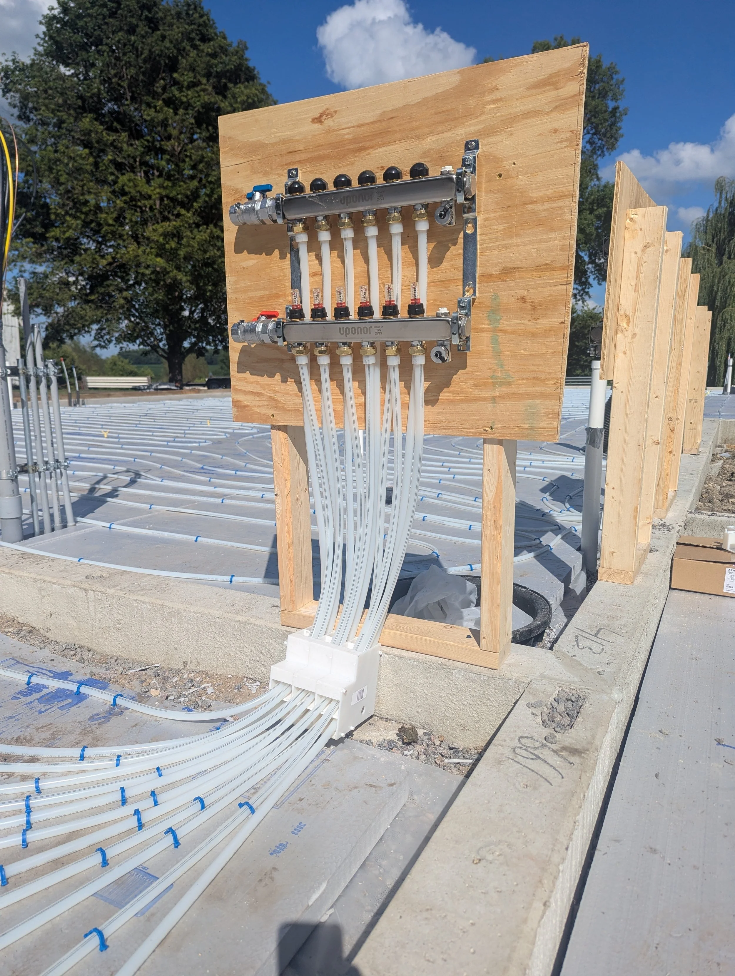 Building construction site with plumbing manifold and tubing for radiant floor heating.