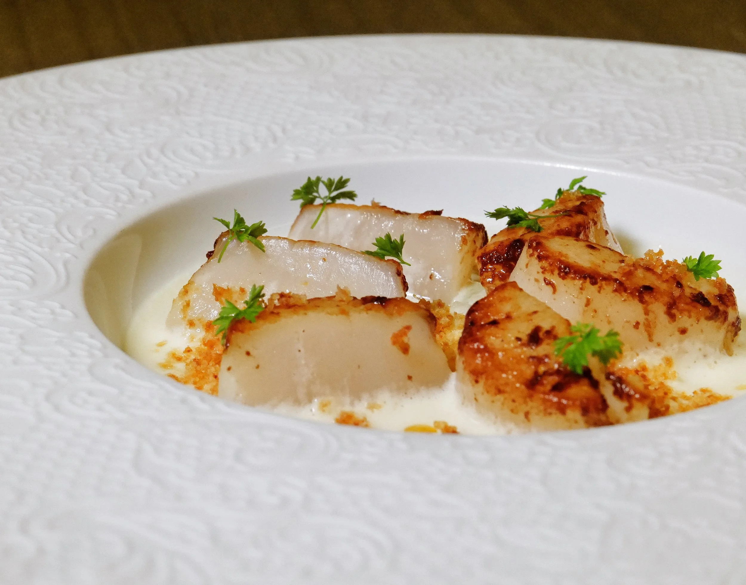 Cooked white fish fillets garnished with parsley on a white textured plate