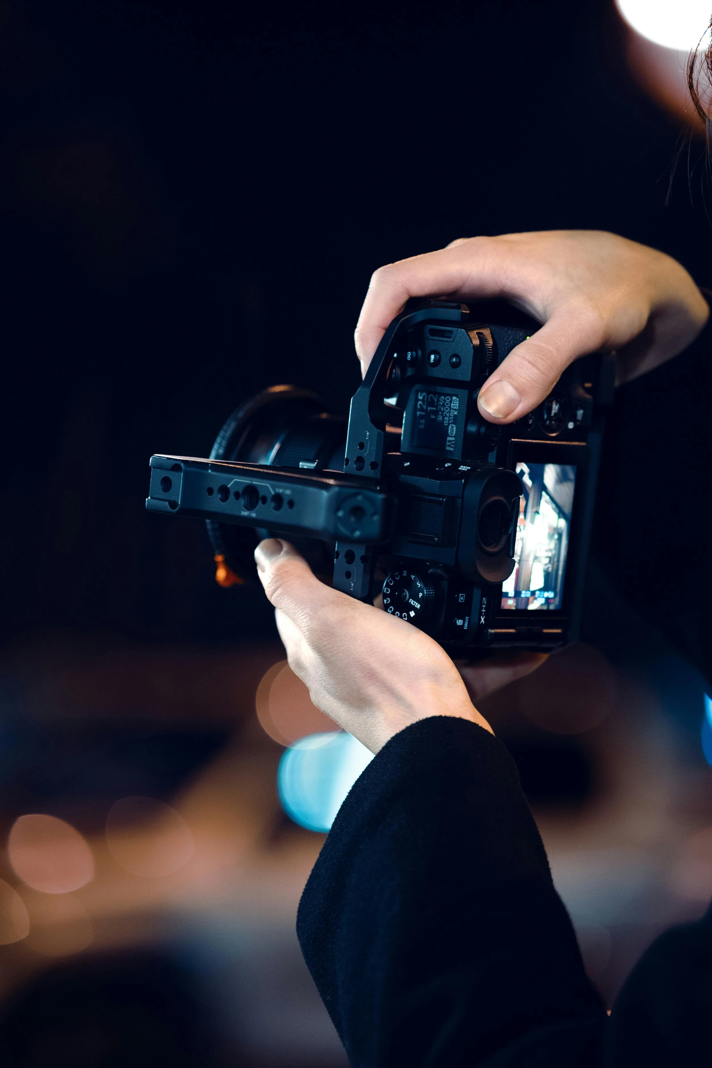 Person holding a professional camera with a mounted stabilizer or rig, capturing a shot at night.