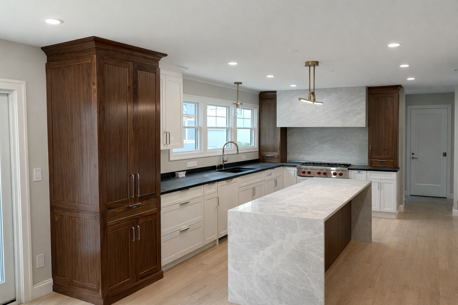 Modern kitchen with white cabinets, dark countertops, a marble island, wooden cabinets, stainless steel stove, and multiple windows.