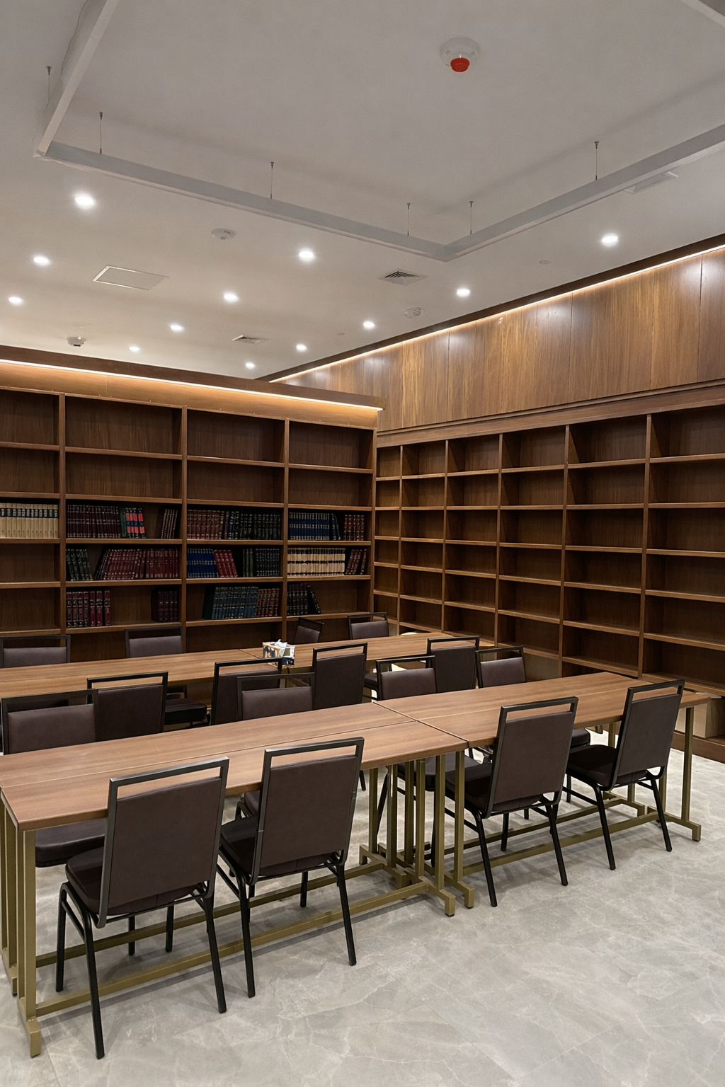 A modern library or conference room with empty bookshelves, tables, and chairs.