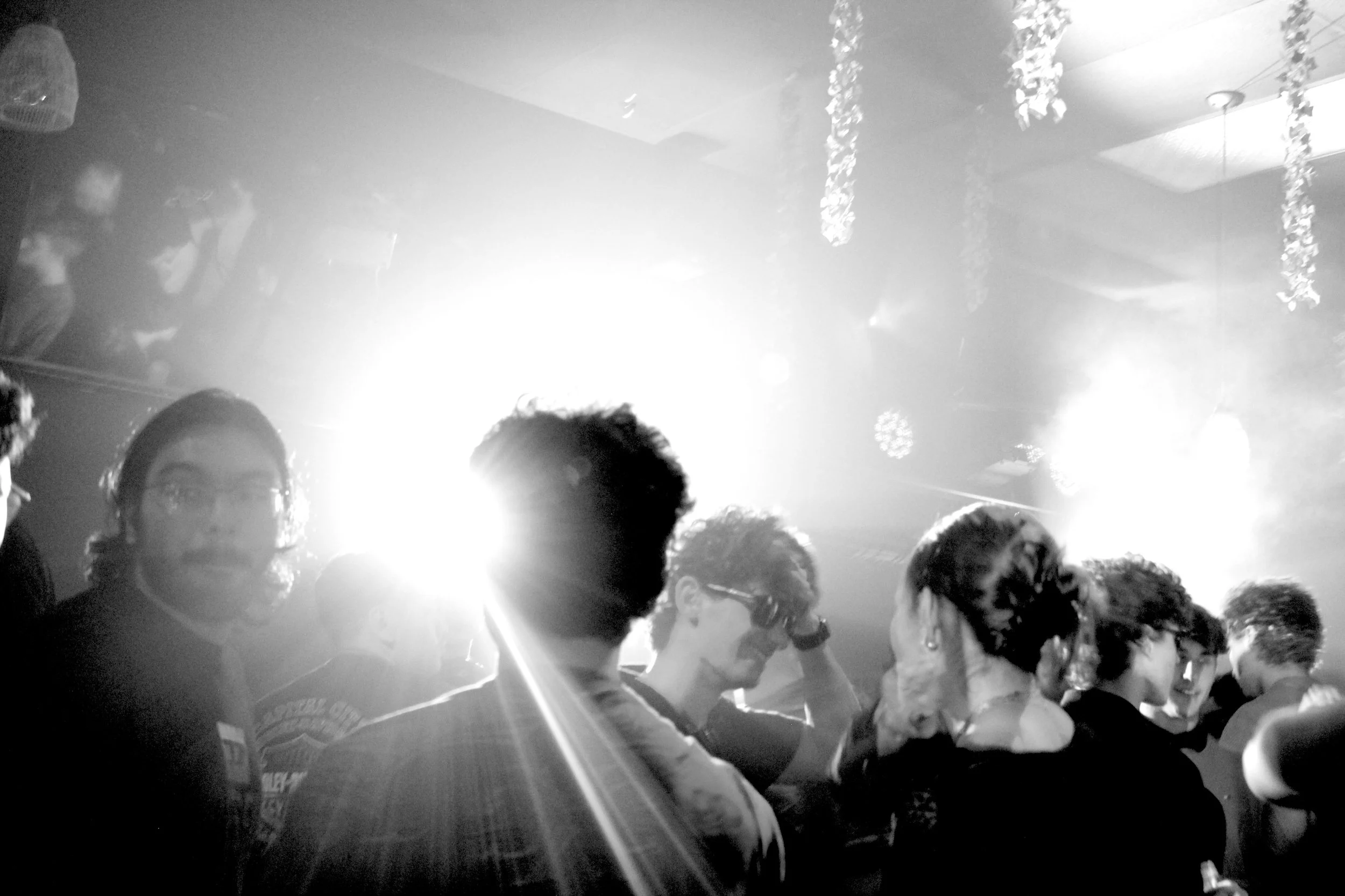 People dancing and socializing at a party with bright lights and decorations hanging from the ceiling.