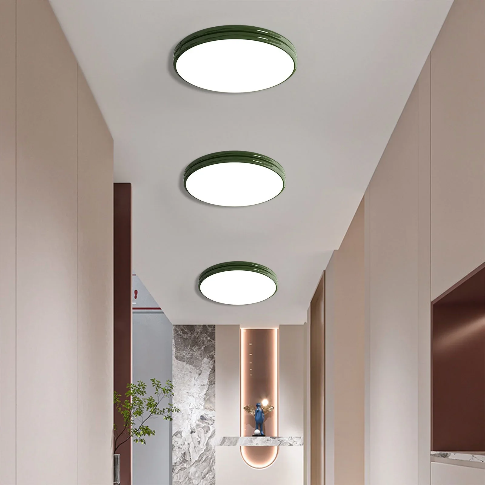 Modern hallway with three round ceiling lights with green trim, beige walls, marble accents, and a decorative figure on a marble ledge in the background.