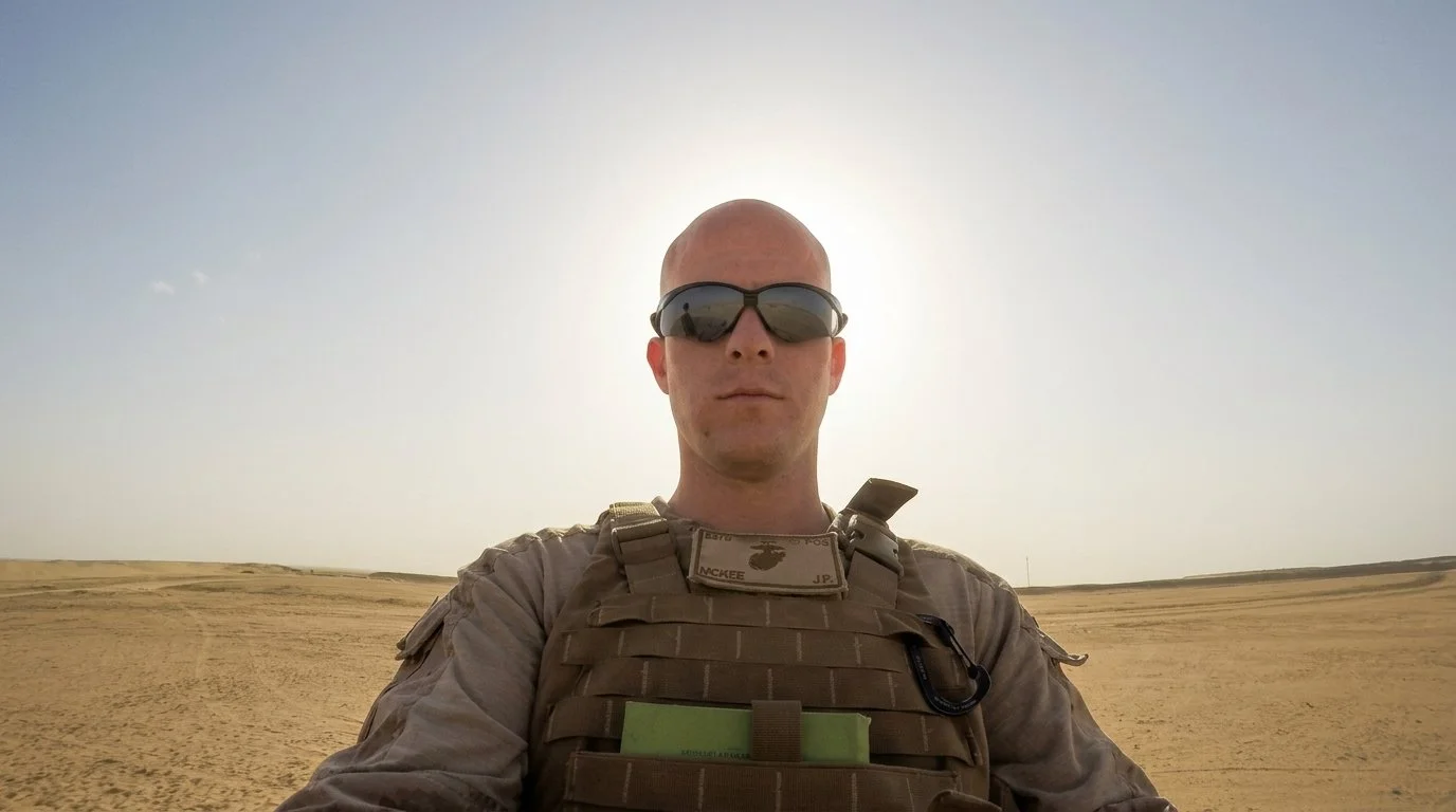 Joseph McKee in military gear standing in a desert with the sun behind their head. The founder of the company, transitioning from raw high-stakes military operations to private sector operations - driving efficiency, earnings, profitability.