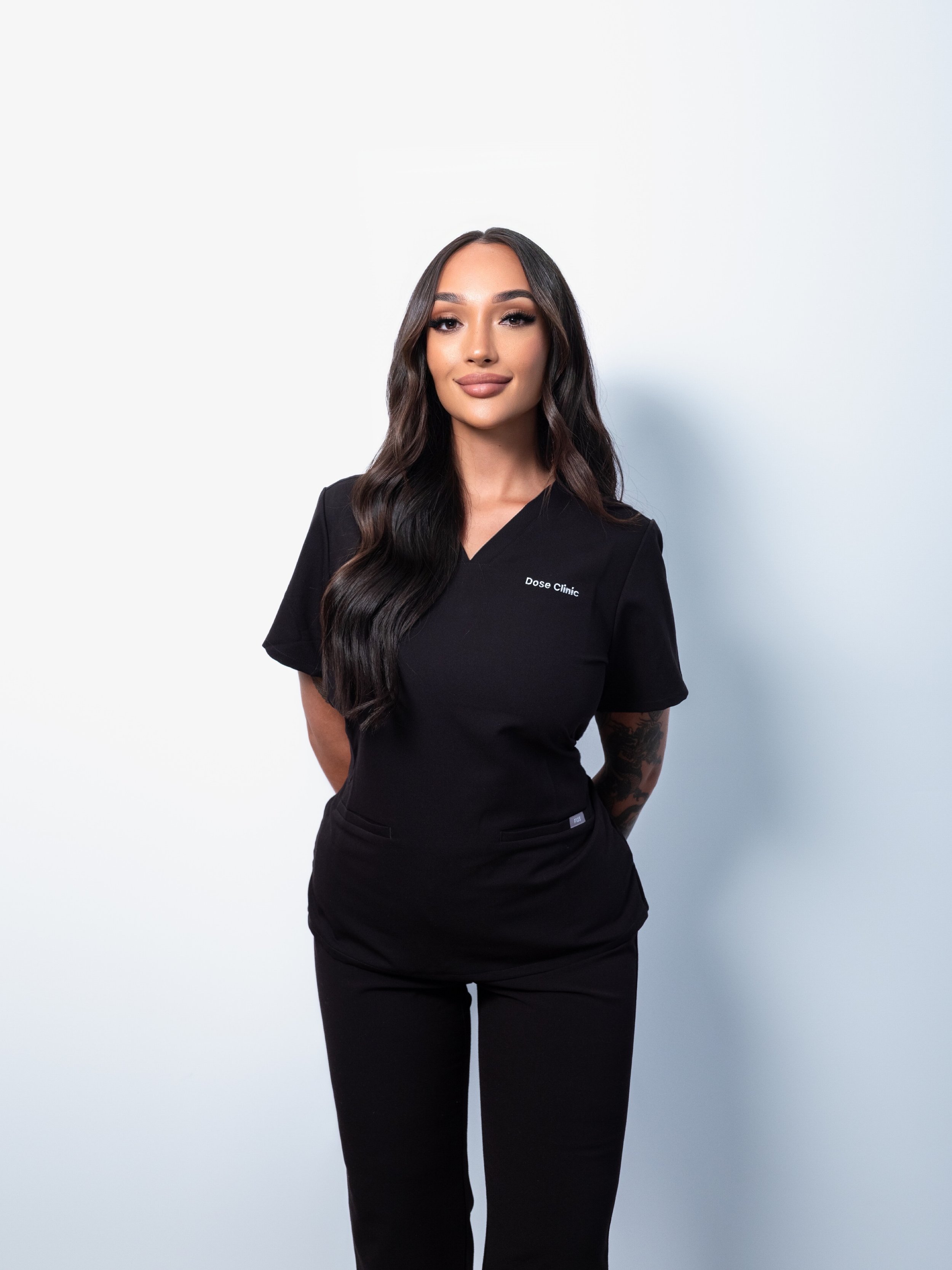 Zara in Dose Clinic scrubs standing against plain background:
Zara co-founder and clinic director Dose Clinic Brisbane | Science-led skin and scalp regeneration West End