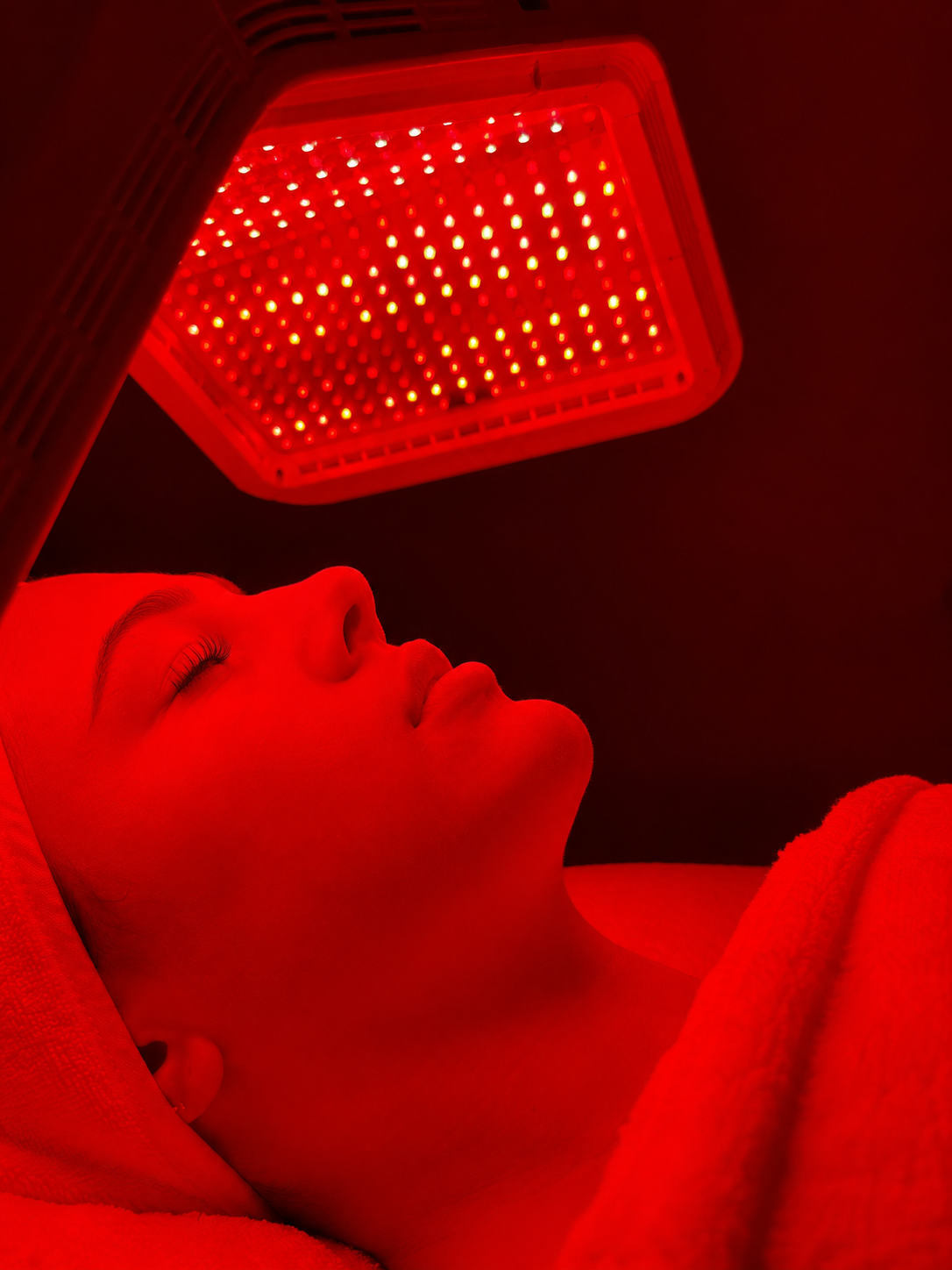Woman under red LED light therapy panel:
LED Light Therapy treatment Brisbane | Reduce inflammation and accelerate skin healing Dose Clinic West End