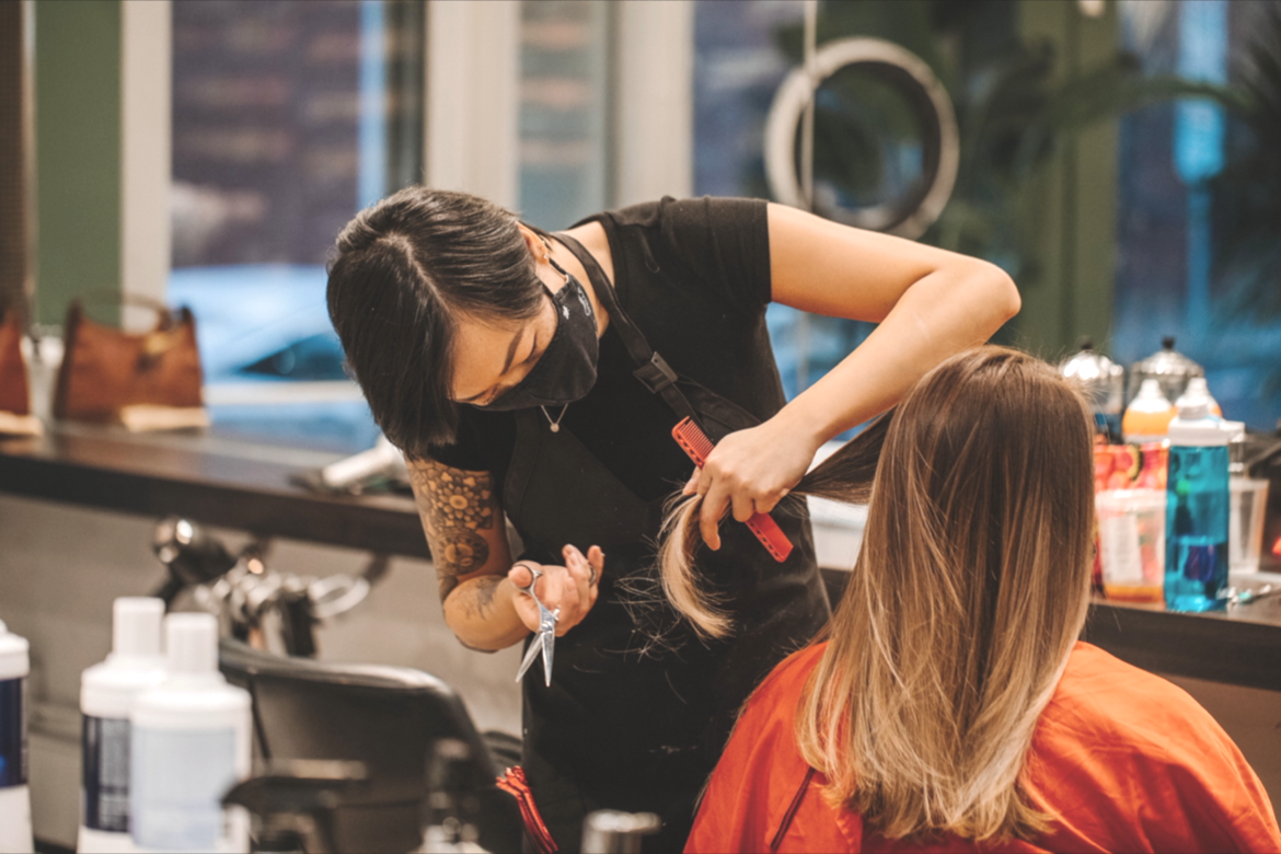 A hairstylist cutting a woman's hair in a salon.