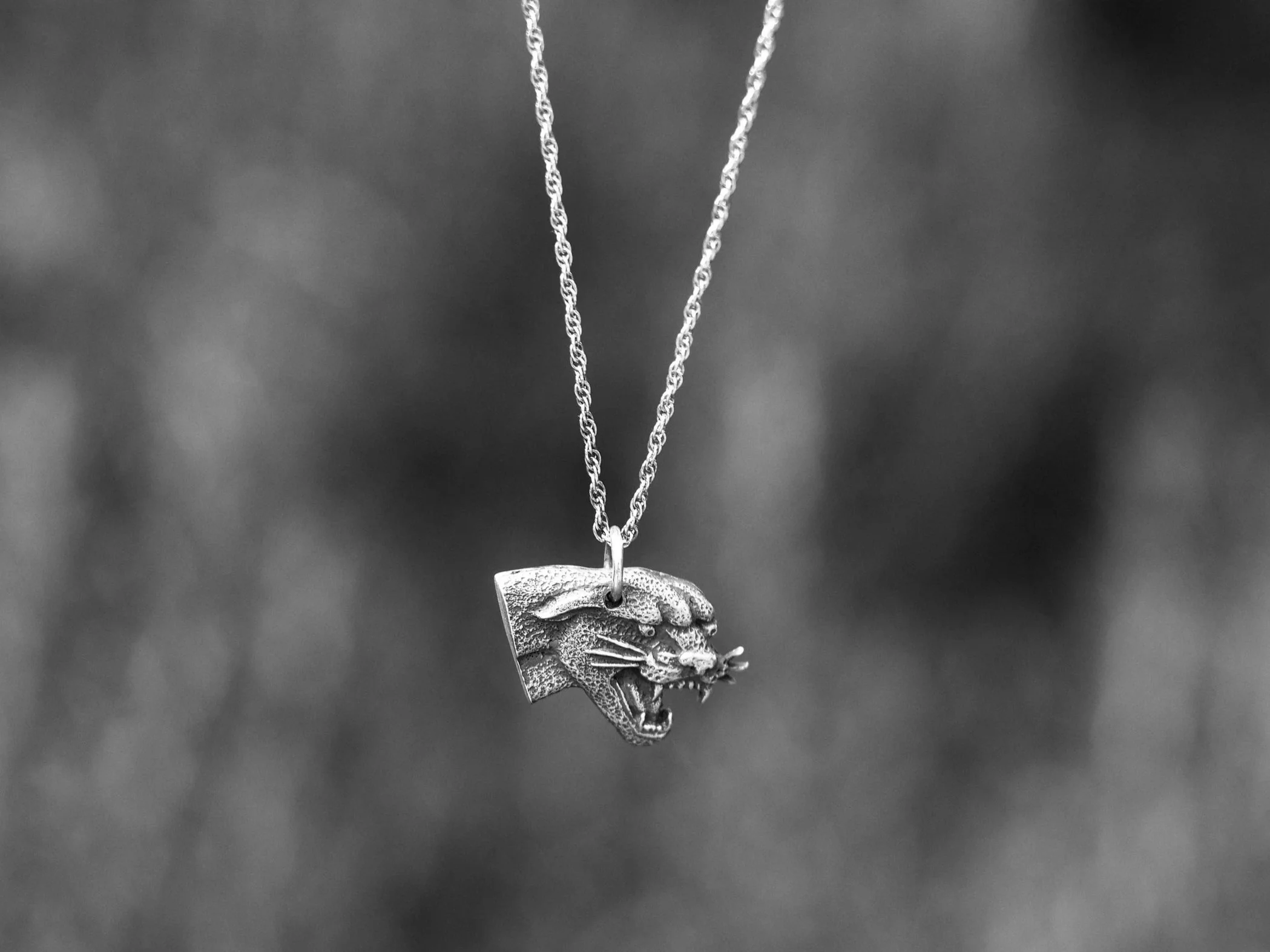 Silver pendant necklace with a tiger's head design hanging from a chain