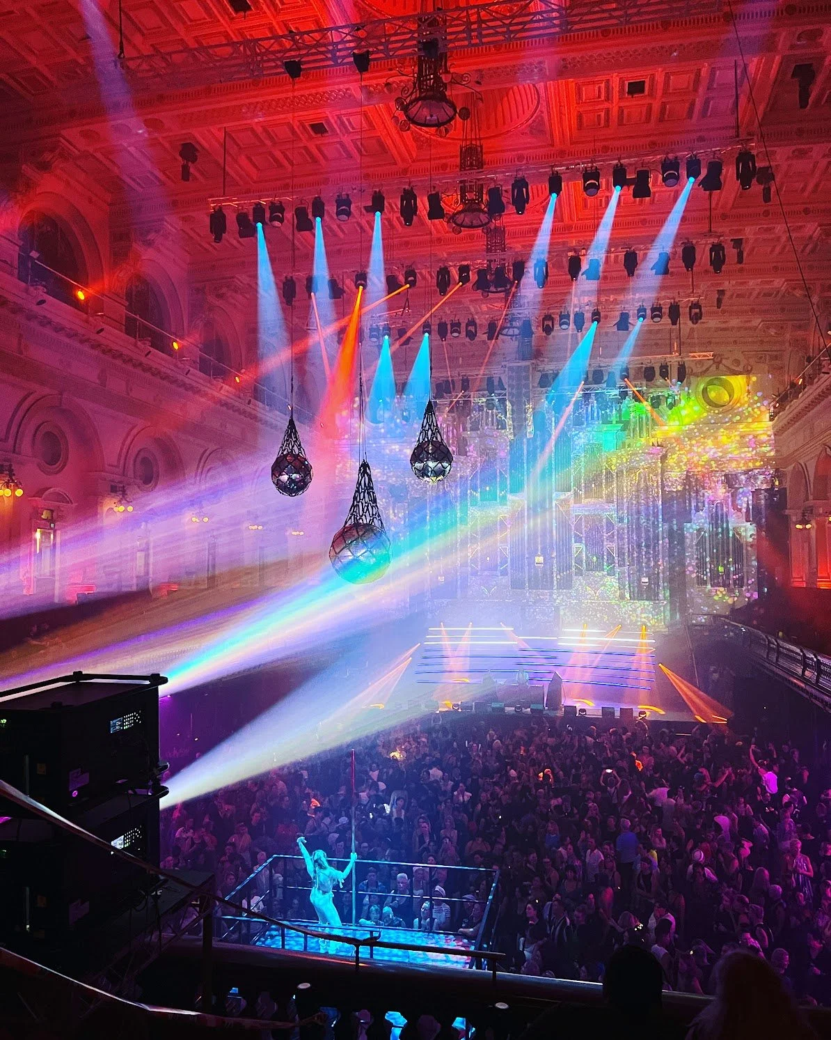 Colorful nightclub scene with a packed dance floor, stage, and vibrant lighting effects.