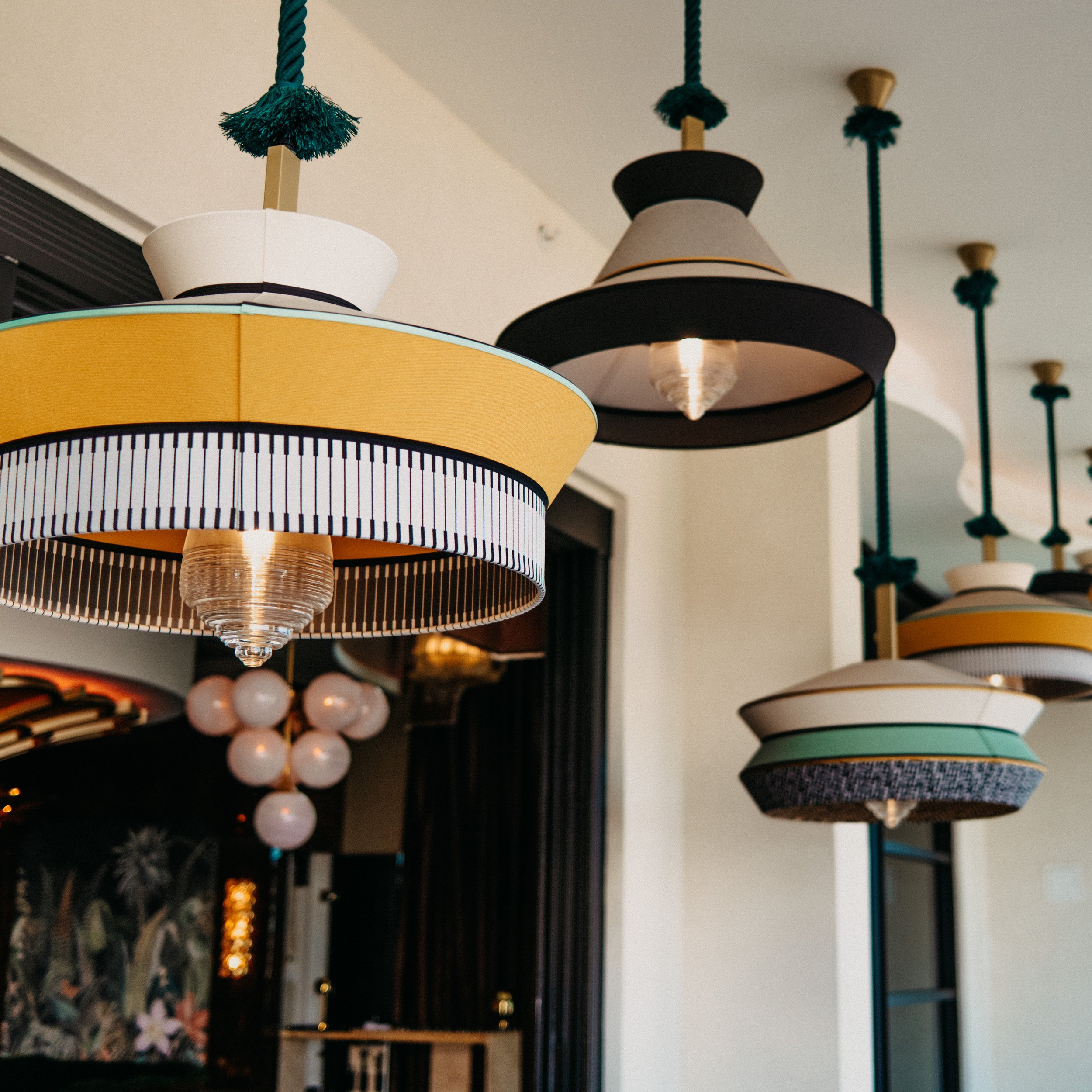 Multiple modern pendant lights with colorful, layered shades hanging from the ceiling in a contemporary interior.