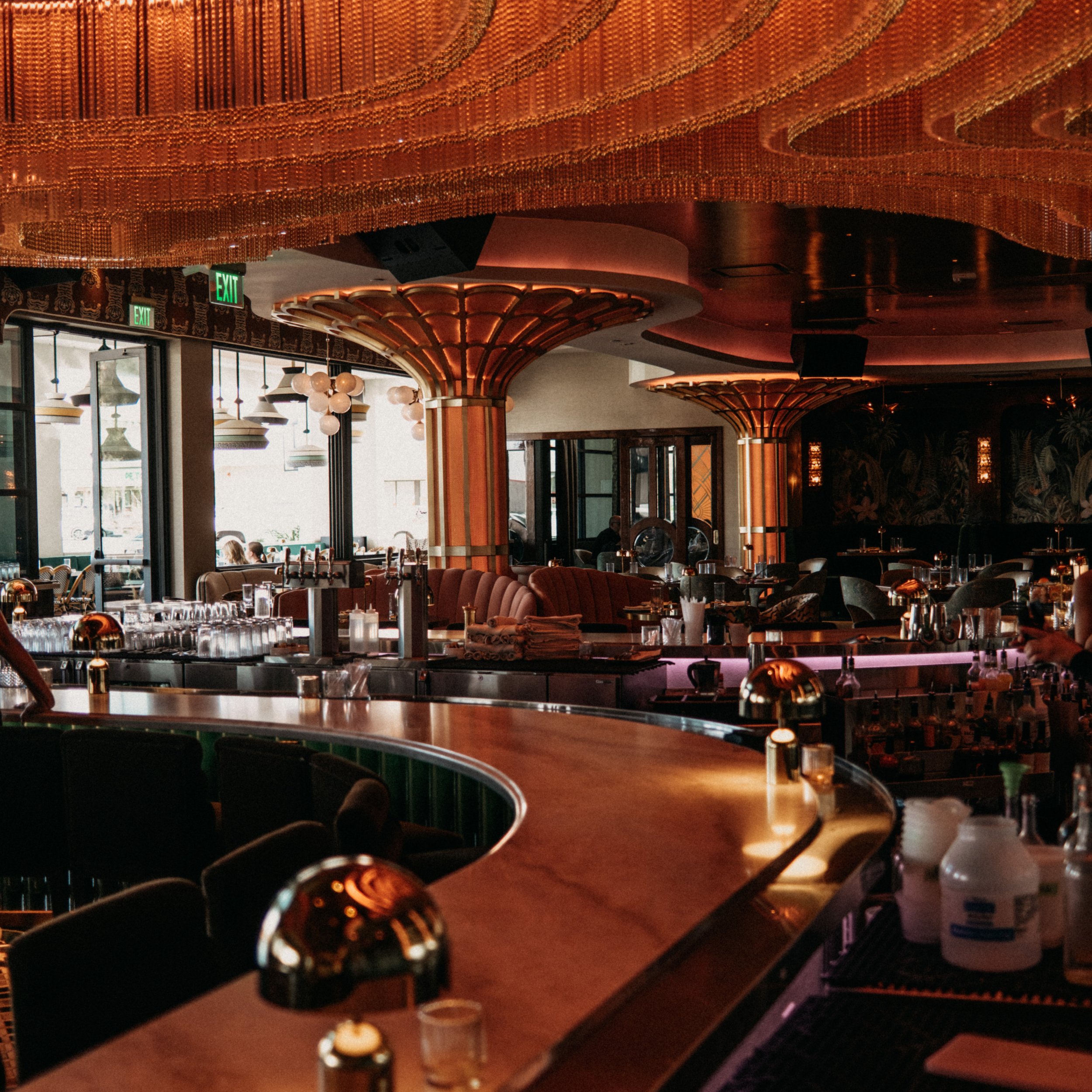 A modern upscale bar and lounge with warm lighting, decorative columns, and large windows.