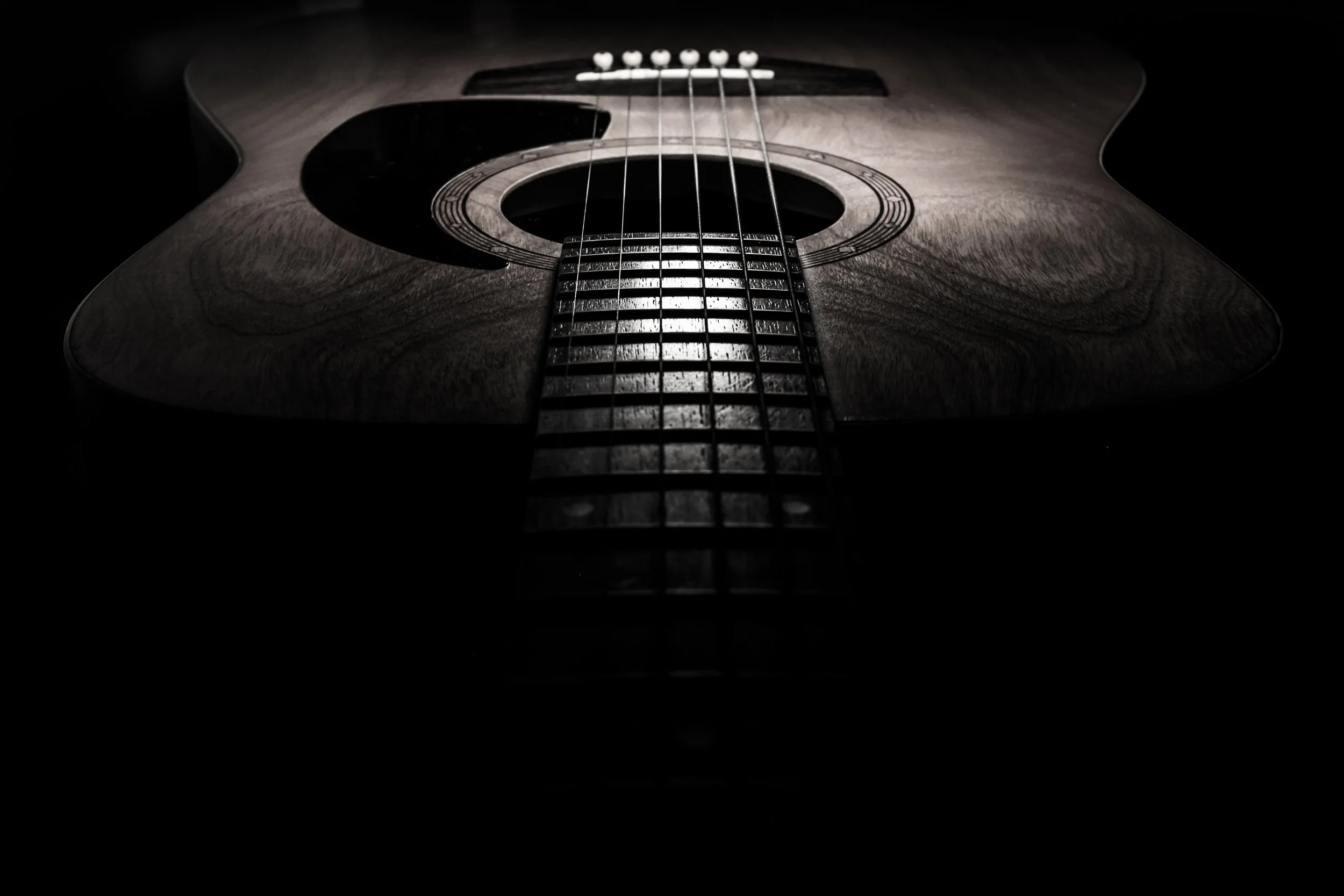Close-up of an acoustic guitar, focusing on the strings and the soundhole, with dramatic lighting emphasizing the wood grain and strings.