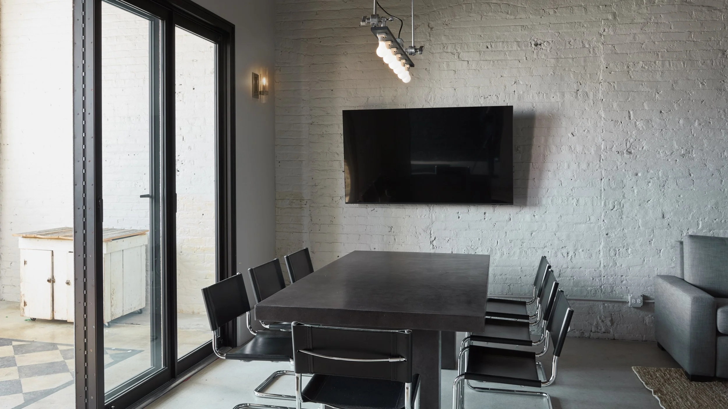 This industrial conference room in Logan Square with long black concrete table, six black chairs, and smart TV, makes this space perfect for meetings, video conferencing, planning sessions and presentations.