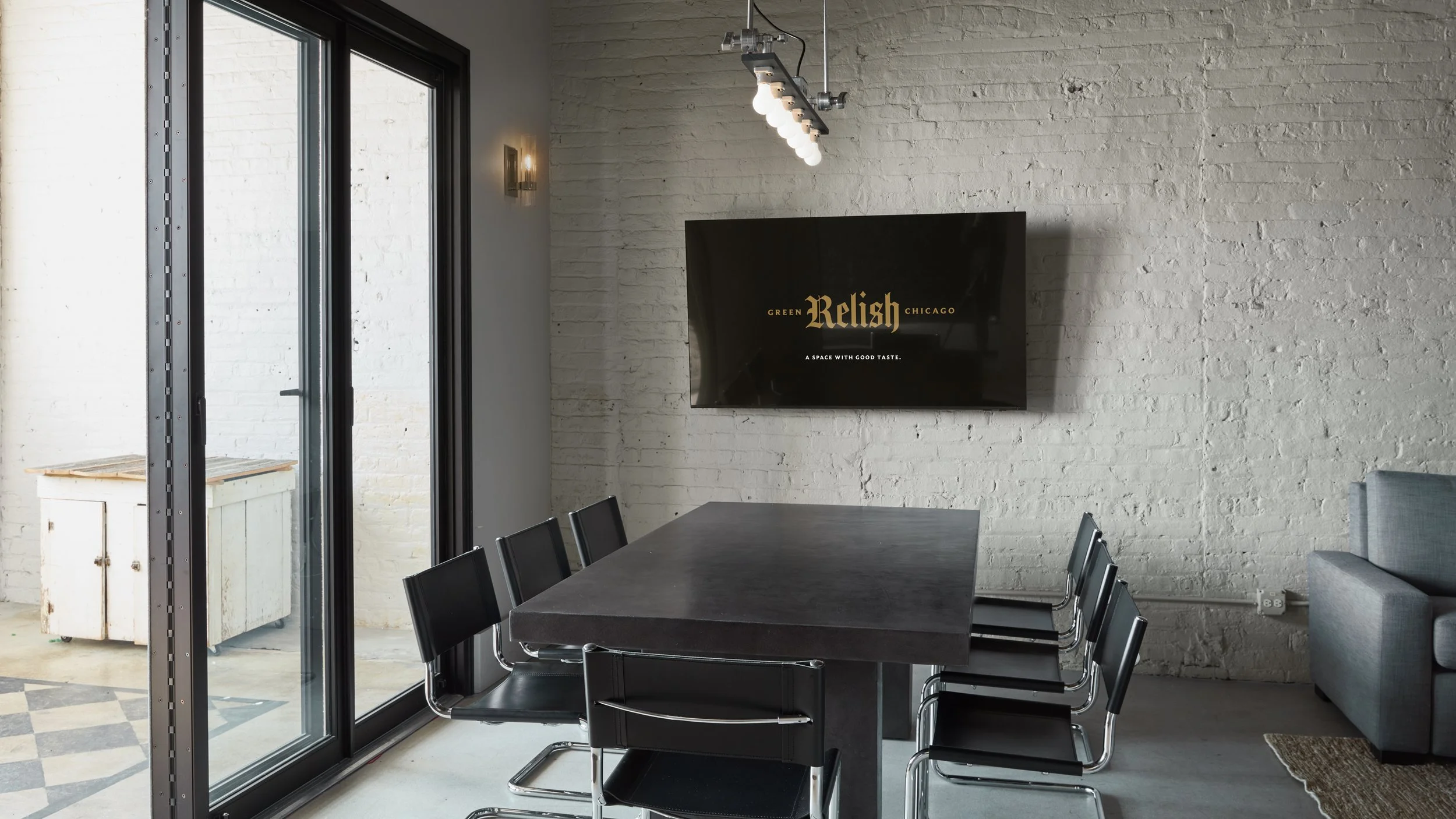 This industrial conference room in Logan Square with long black concrete table, six black chairs, and smart TV, makes this space perfect for meetings, video conferencing, planning sessions and presentations.