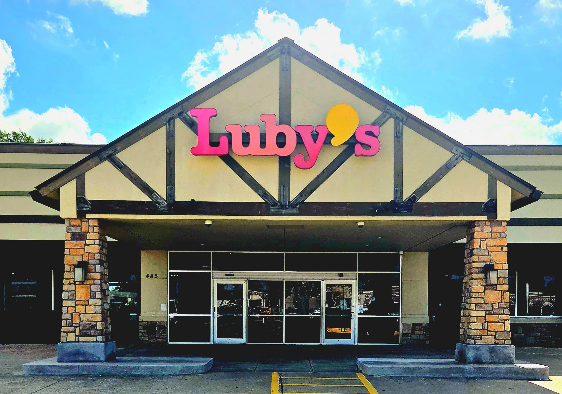 Exterior of a building with a sign that says "Luby's" in pink letters, under a partly cloudy sky.