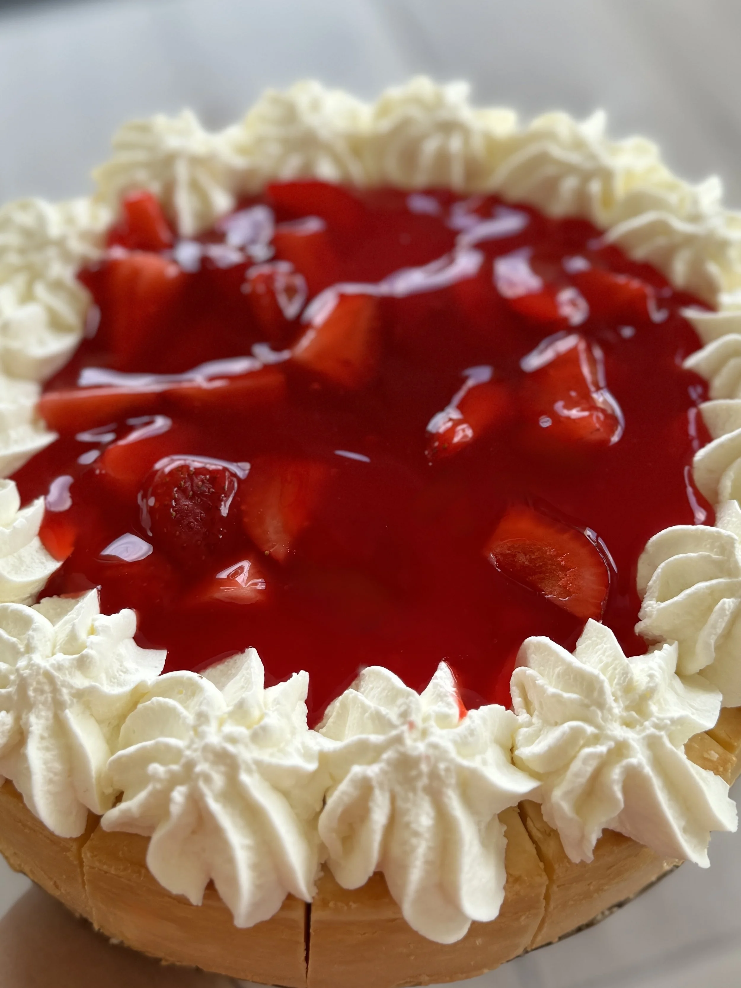 Close-up of a dessert with whipped cream border, strawberry topping, and small pieces of strawberries.