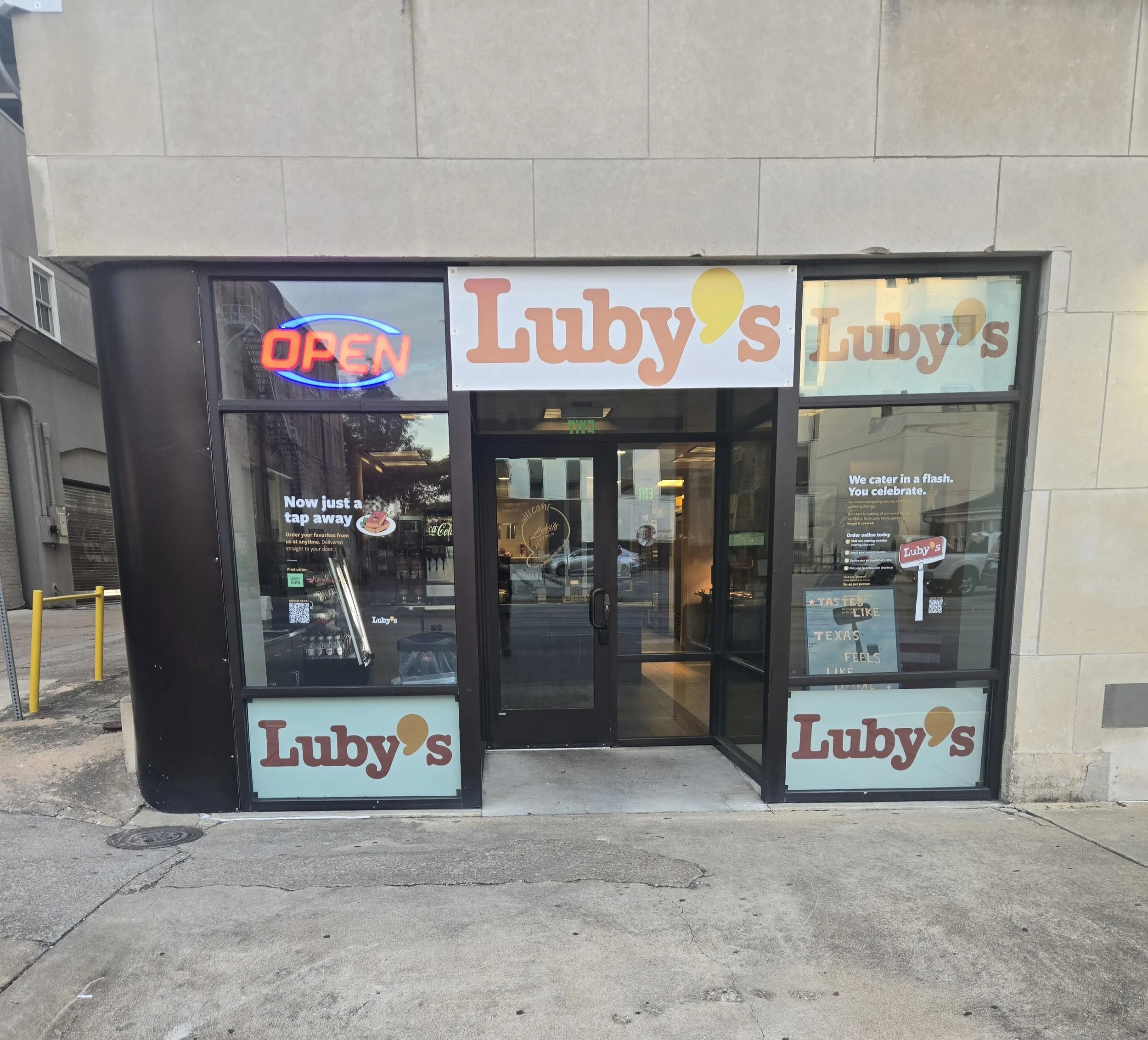 storefront with signs for Lulu's, an open neon sign, and advertisements for catering and online ordering at Lulu's