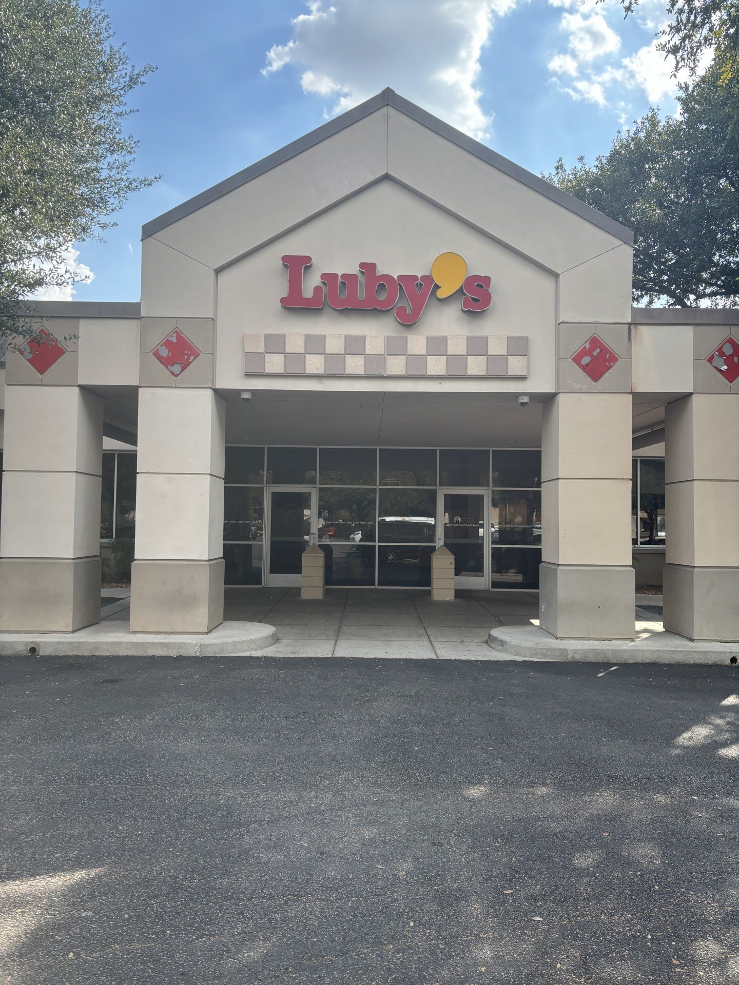 Front view of Luby's restaurant building with a sign above the entrance, beige exterior walls, and a paved parking lot in the foreground.
