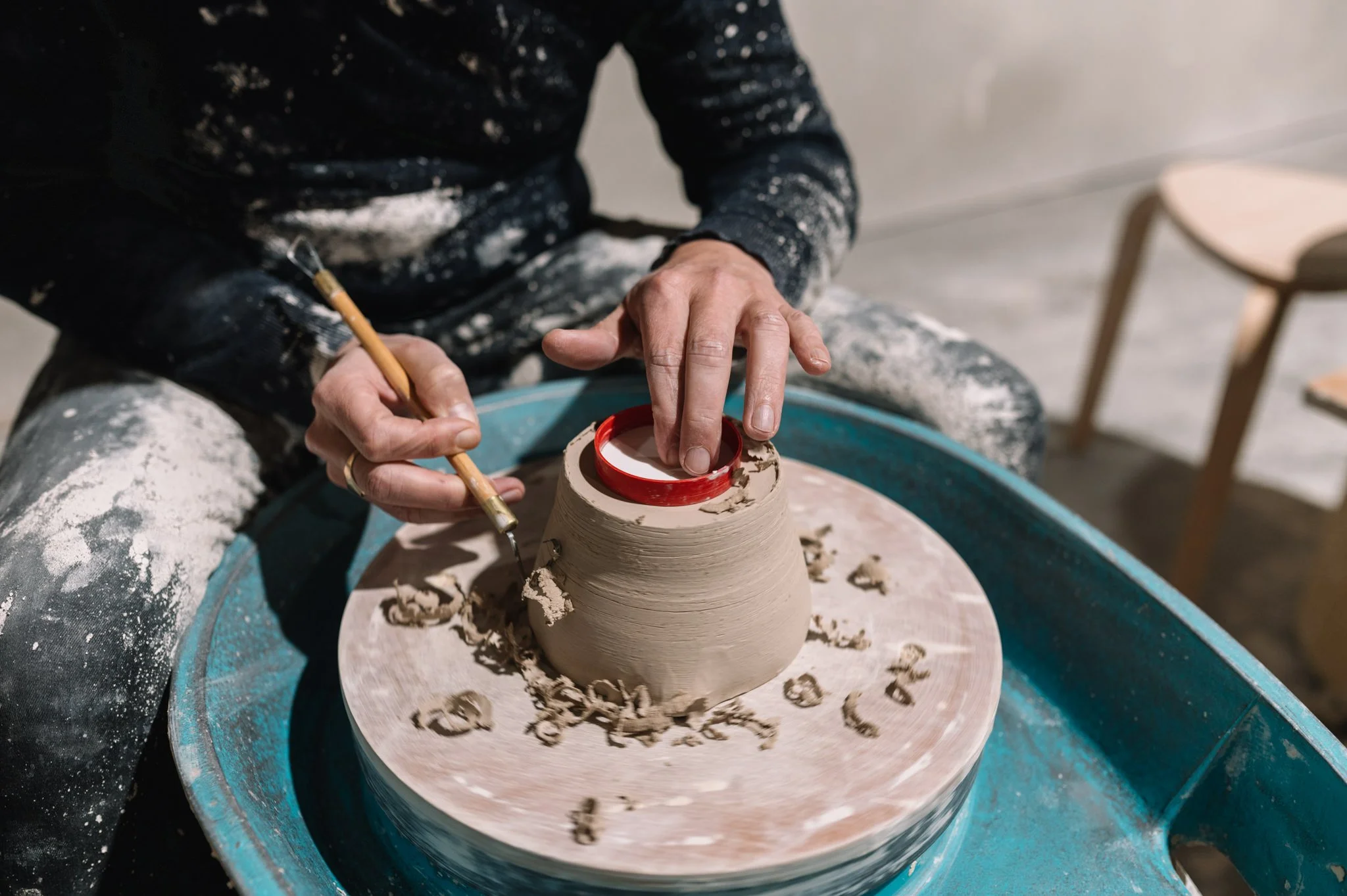 Close-up of trimming a clay pot on a pottery wheel during a ceramics class in Tasmania