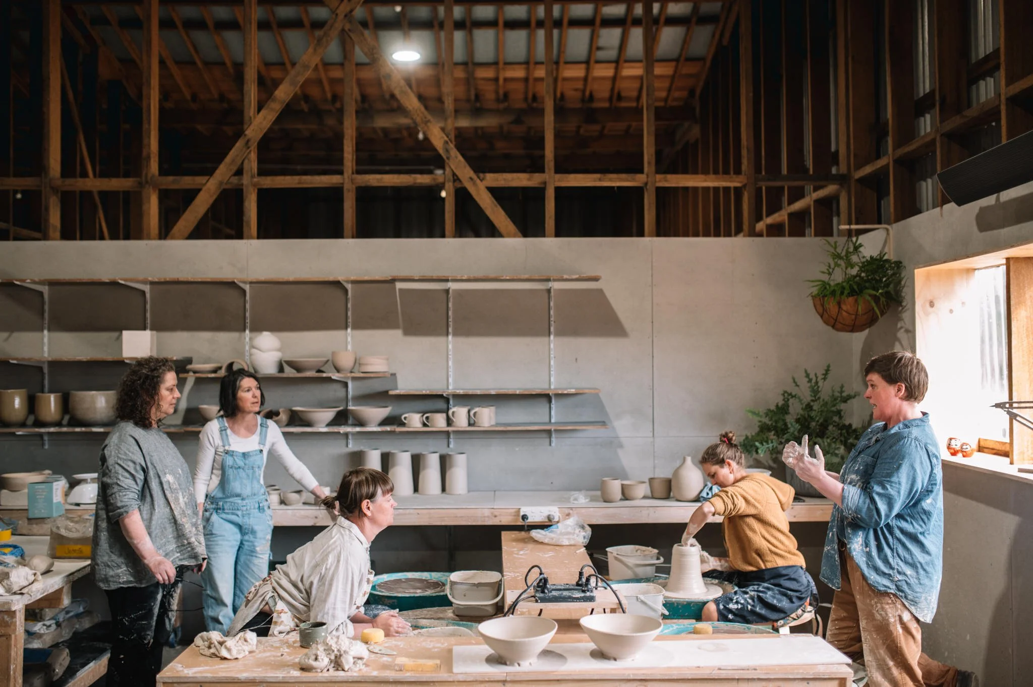 Students gathered around a table discussing handmade ceramics during a pottery course in Tasmania