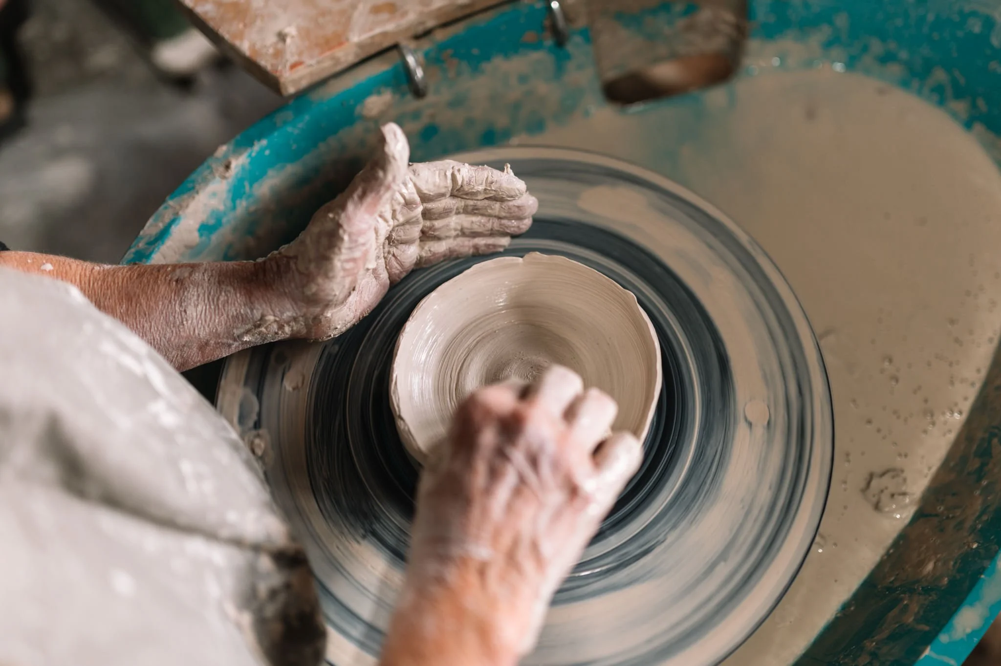 Close-up of hands shaping a bowl on a pottery wheel in a beginner ceramics class