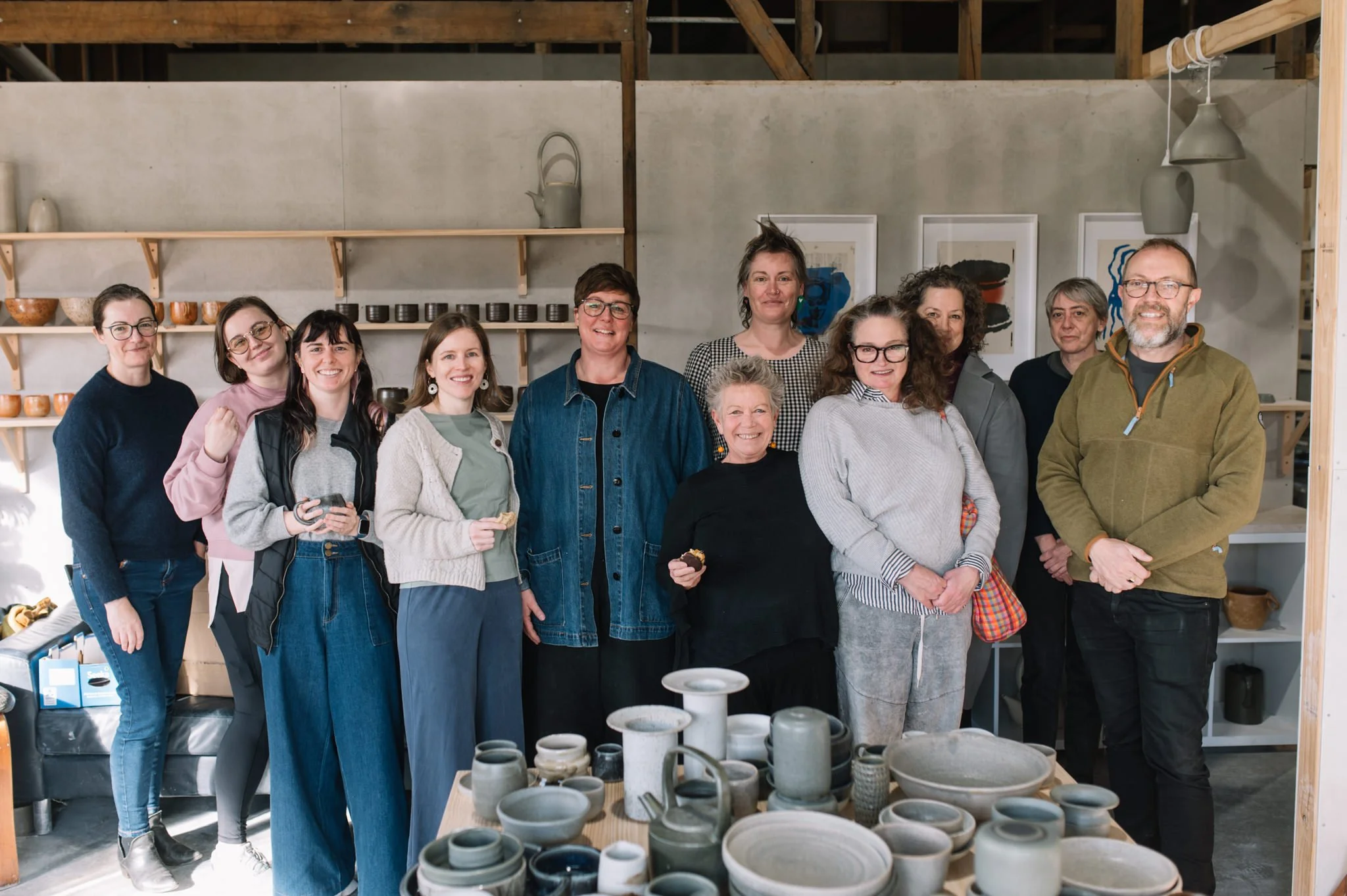 Group of pottery students and makers at Huon Valley Pottery studio in Tasmania surrounded by handmade ceramics
