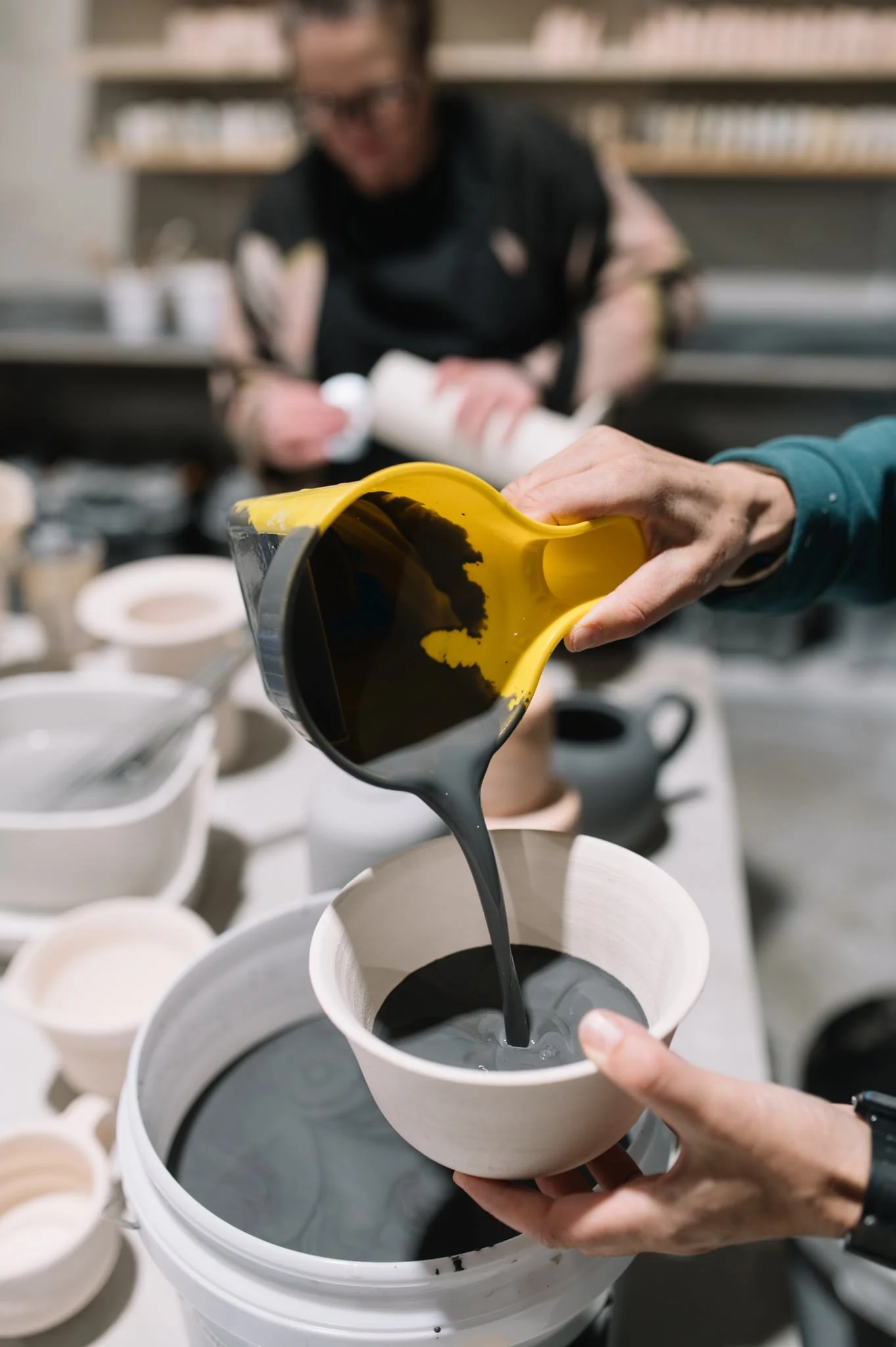 pouring glaze onto handmade ceramic bowl in pottery studio