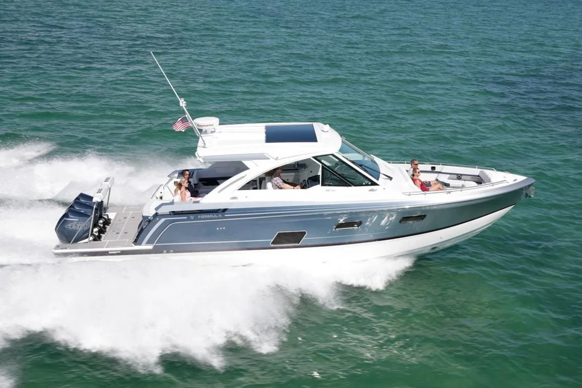 A white and gray motor yacht speeding across a body of water with four people onboard enjoying the ride.
