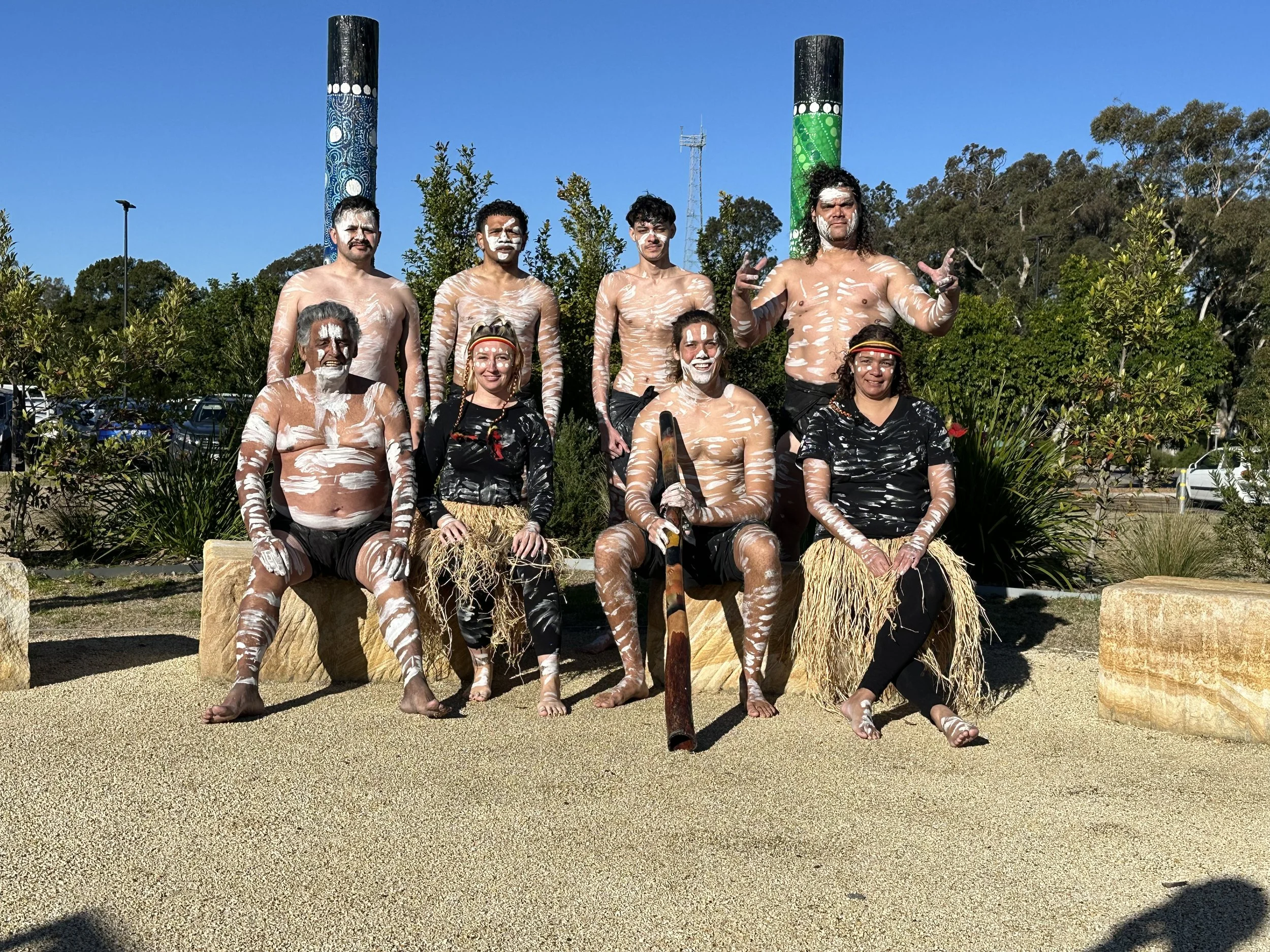 Group of people sitting and standing outdoors on a sunny day.