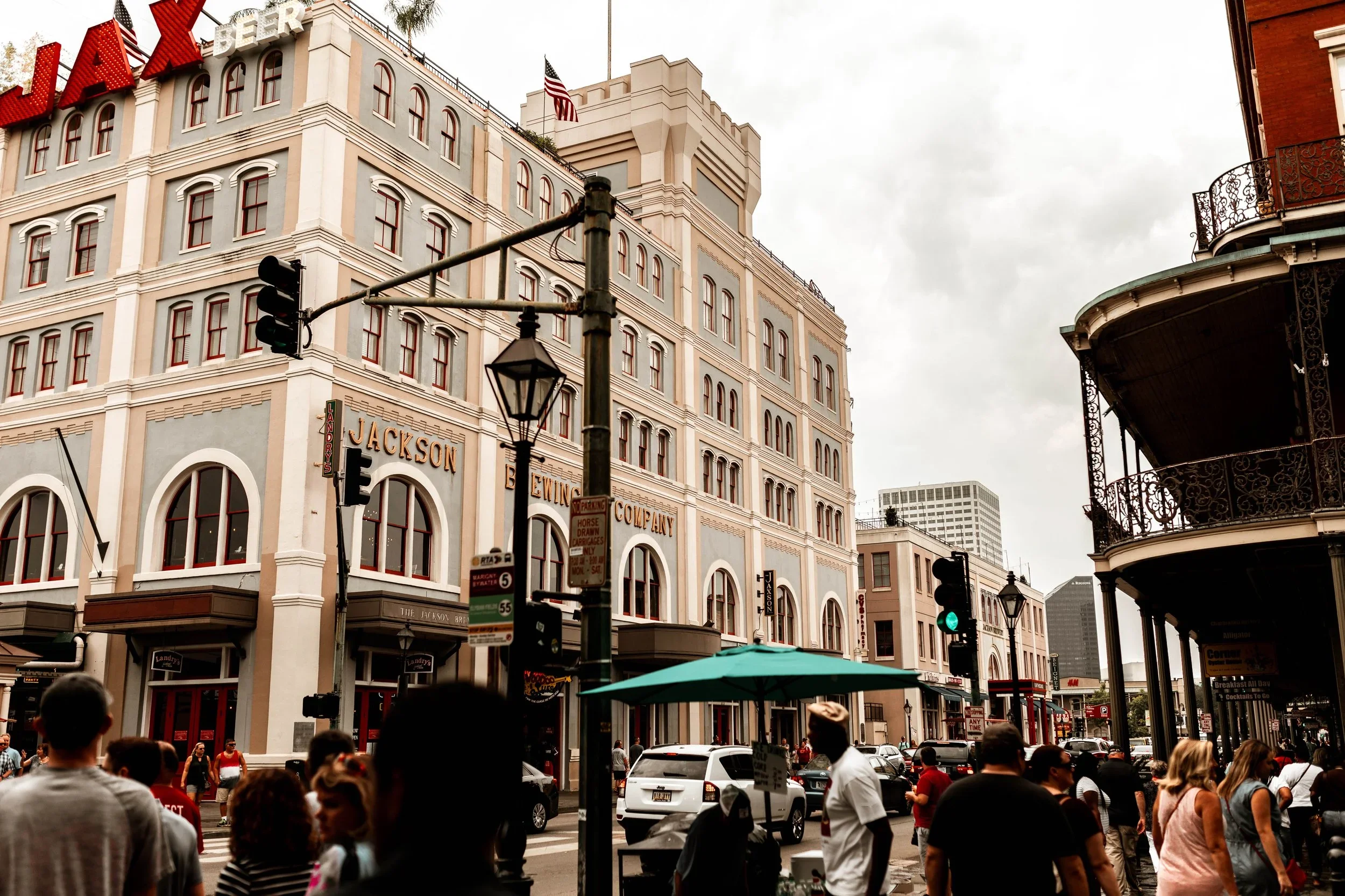 A travel photo by Photos by Elliot depicting a busy city street with people walking and cars, historic buildings with signs, and a cloudy sky.