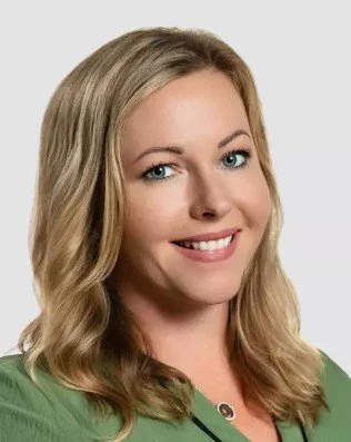 Portrait of a smiling woman with blonde hair wearing a green top.