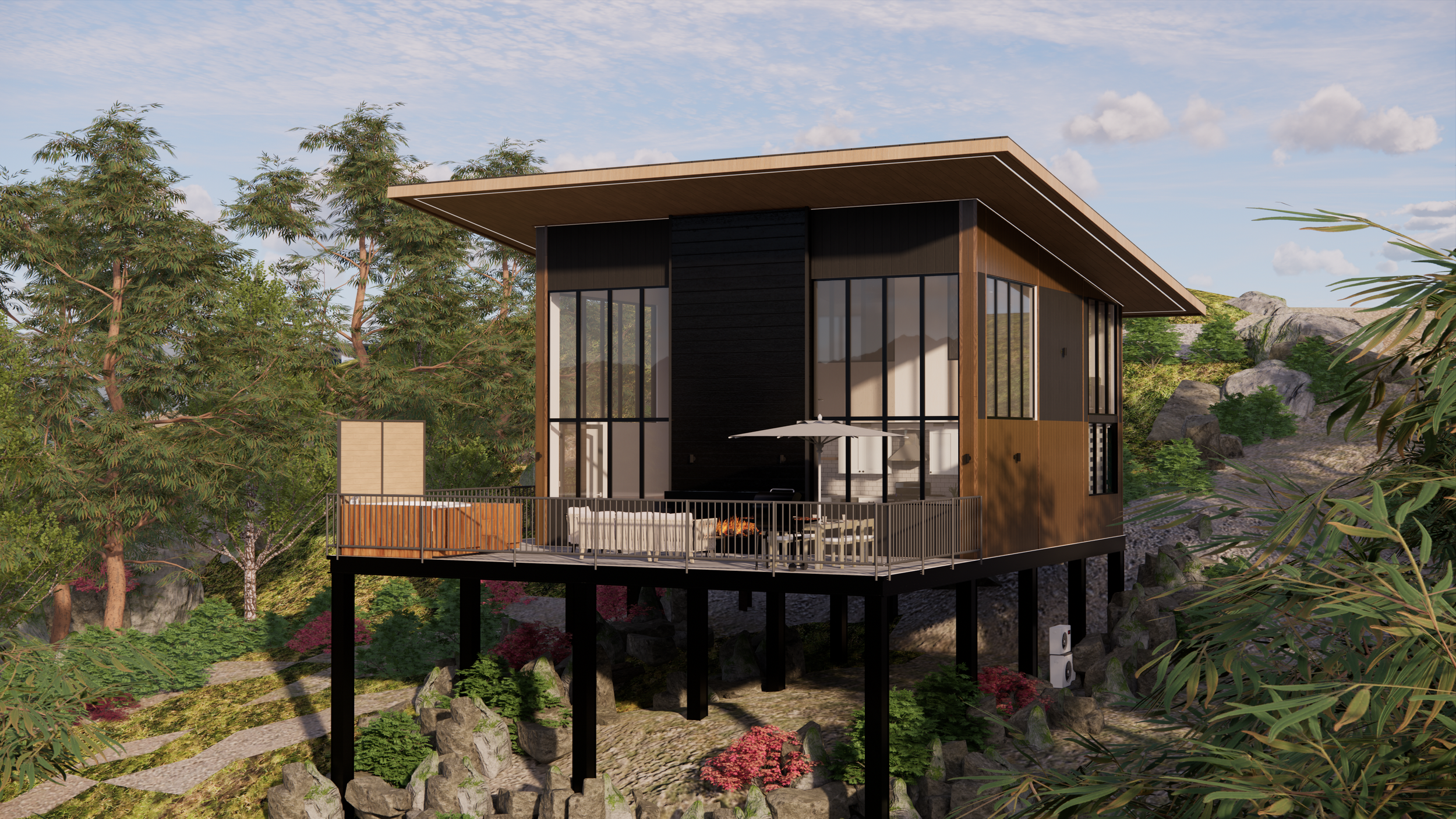 Modern house on stilts with large glass windows, an outdoor balcony with seating and umbrella, set in a lush green landscape with rocks and trees.