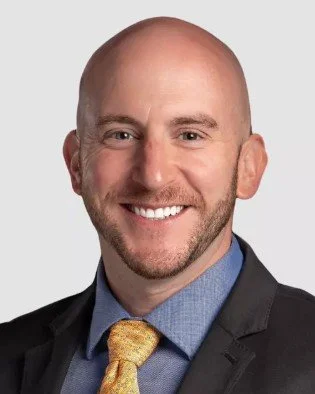 Professional headshot of a smiling man in a suit and tie