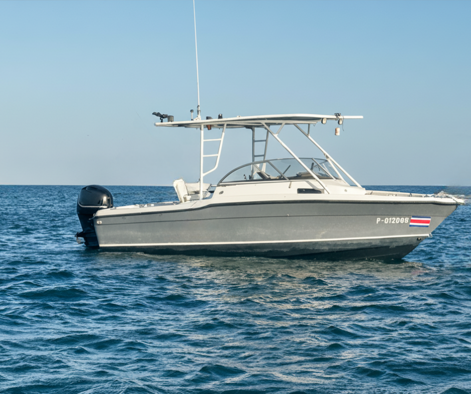 A small gray recreational boat on calm ocean water with a clear sky in the background.