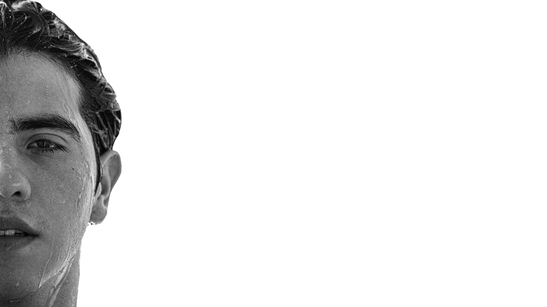 Close-up of Ray Maldonado with wet hair, with water droplets on his face, looking directly at the camera, against a white background.